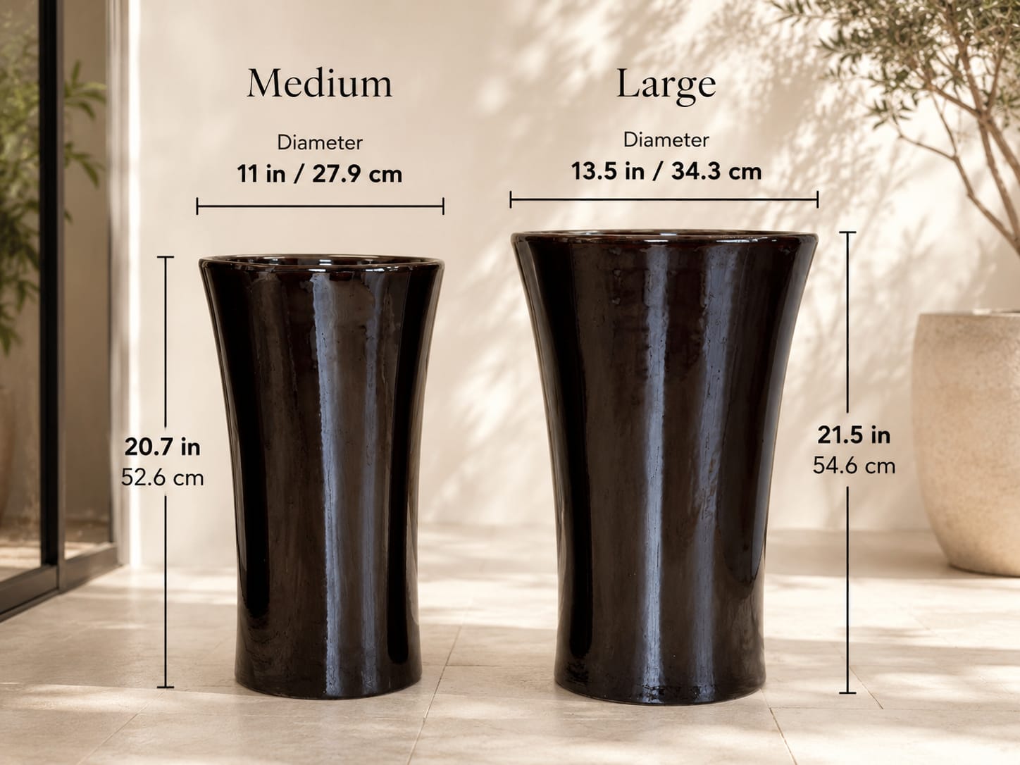 Two dark ceramic pedestal vases with size labels on a showroom wall.