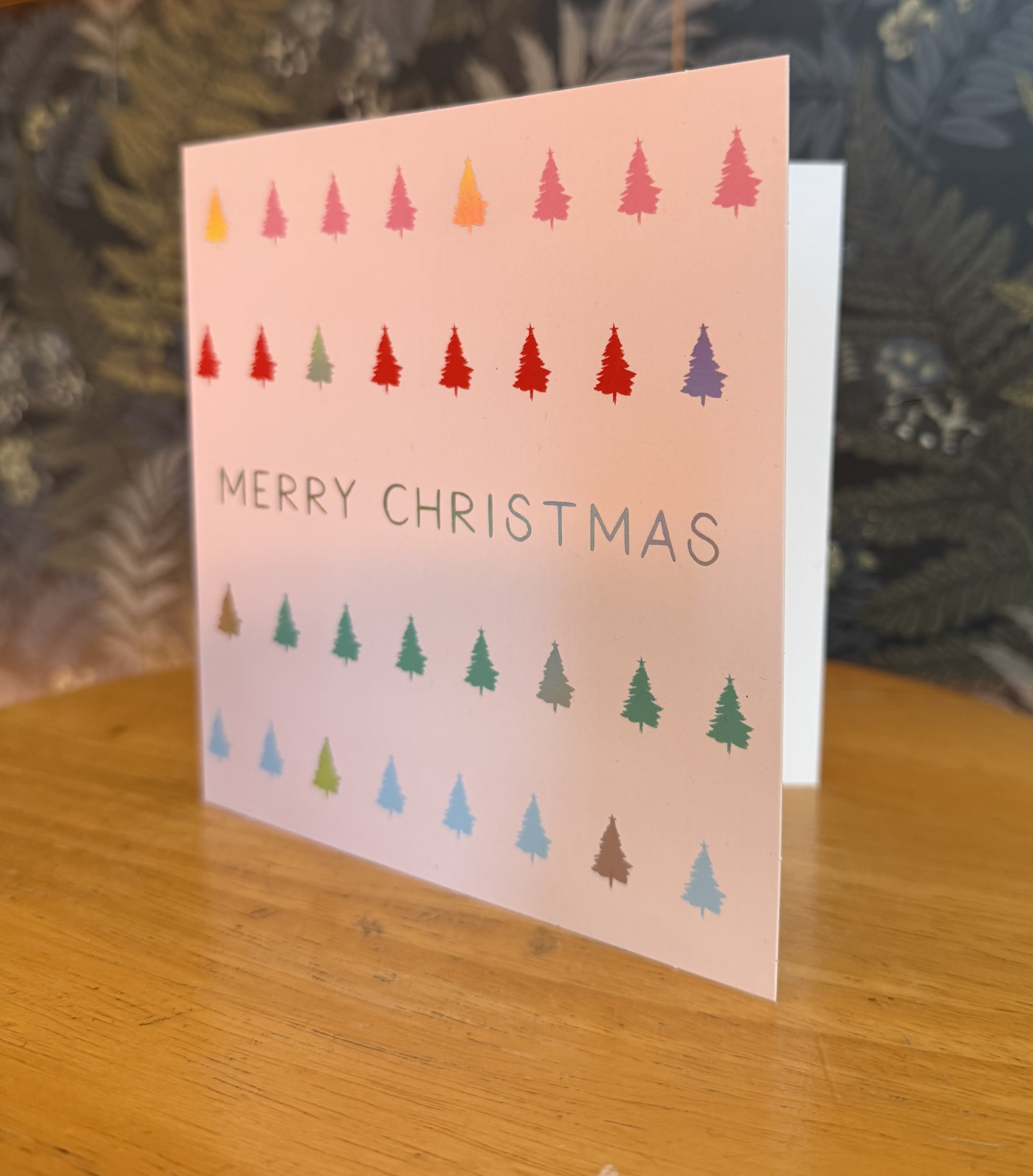 A pink Christmas card with multicolored tree icons and "Merry Christmas" text.