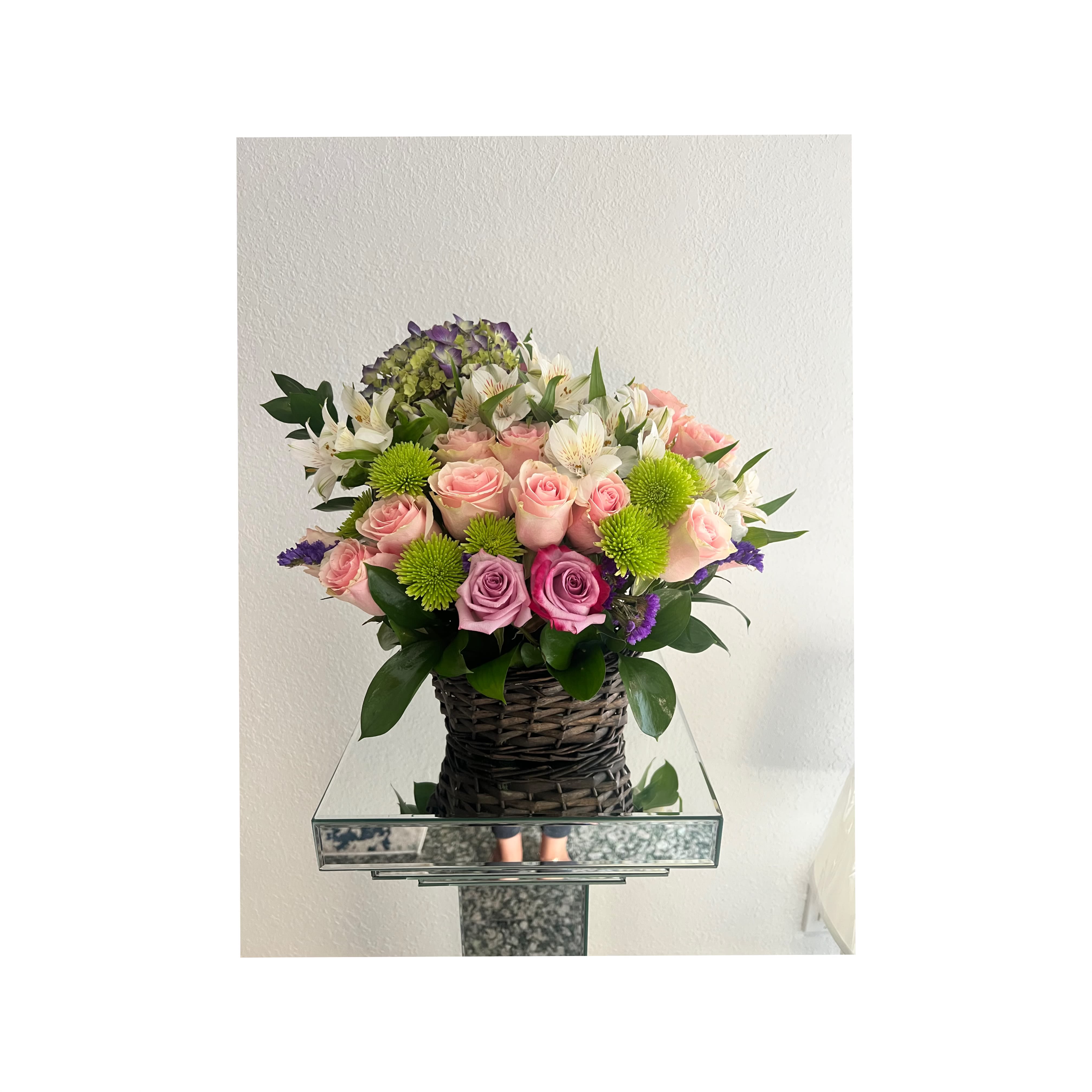 Bouquet of pink roses and white alstroemeria in a woven basket