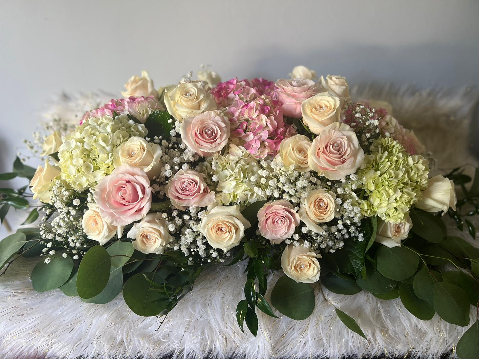 Low arrangement of pink and cream roses with hydrangeas and baby's breath