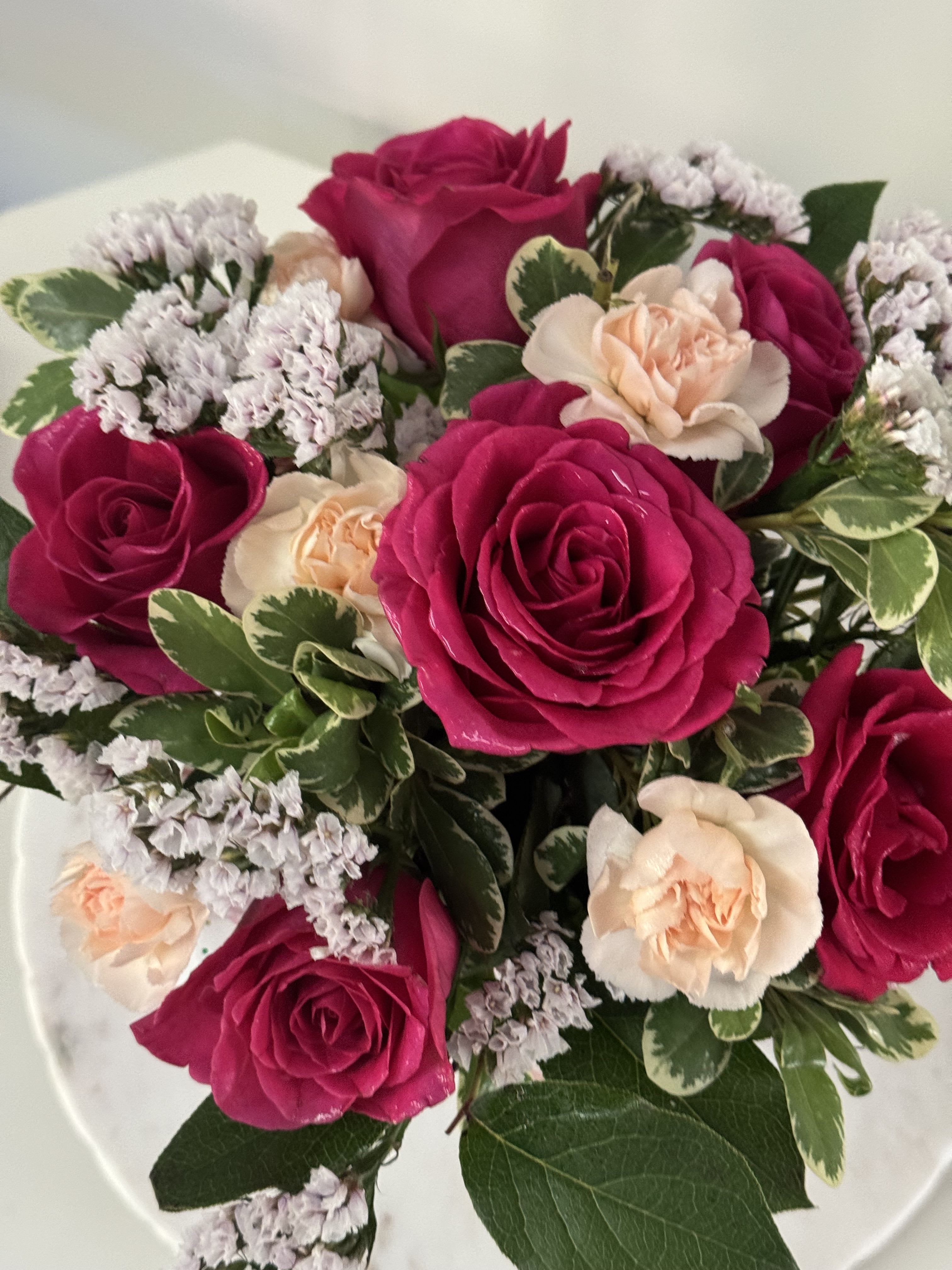 Bouquet of hot pink and peach roses with small white filler flowers