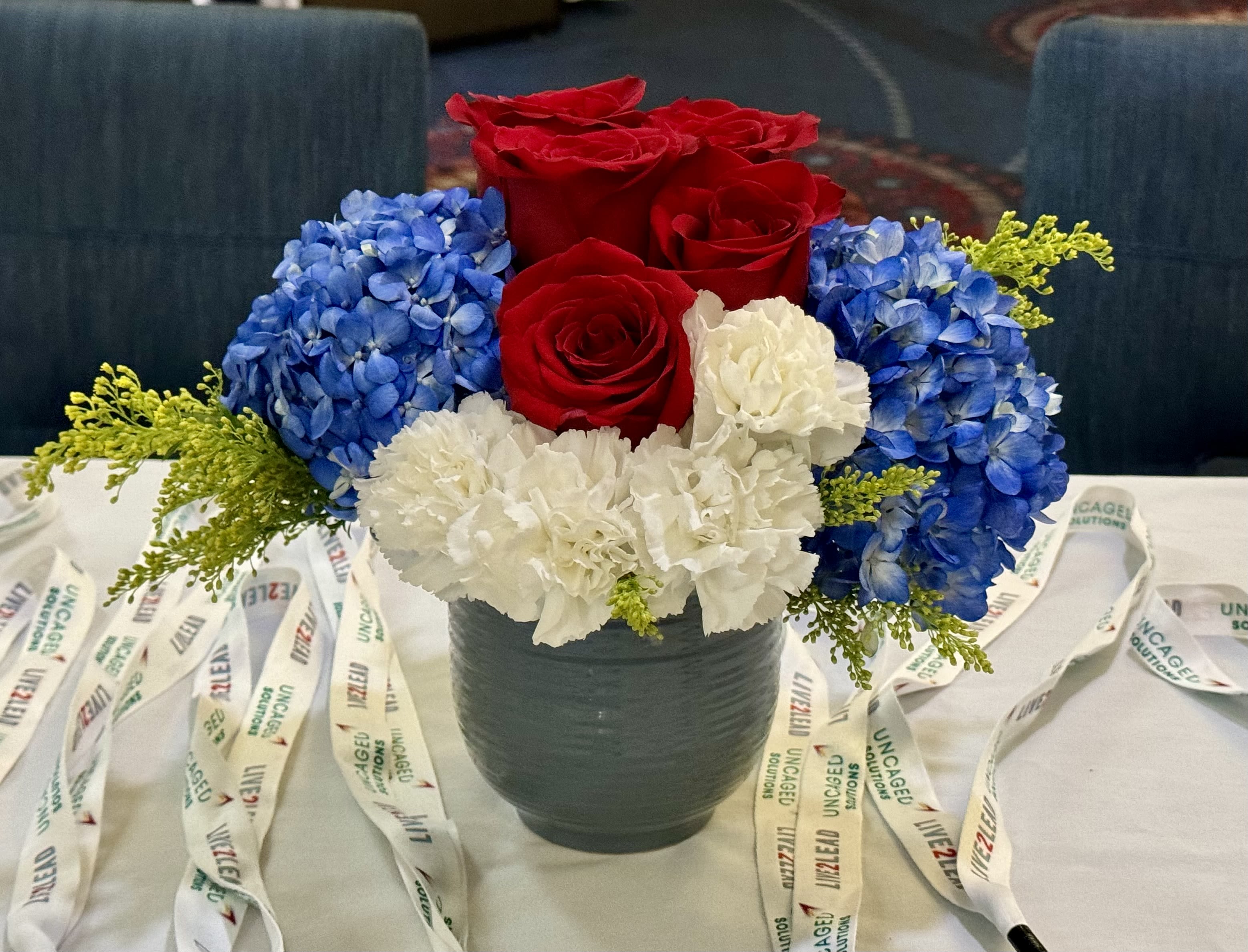 Red roses, blue hydrangeas, and white carnations in a dark vase
