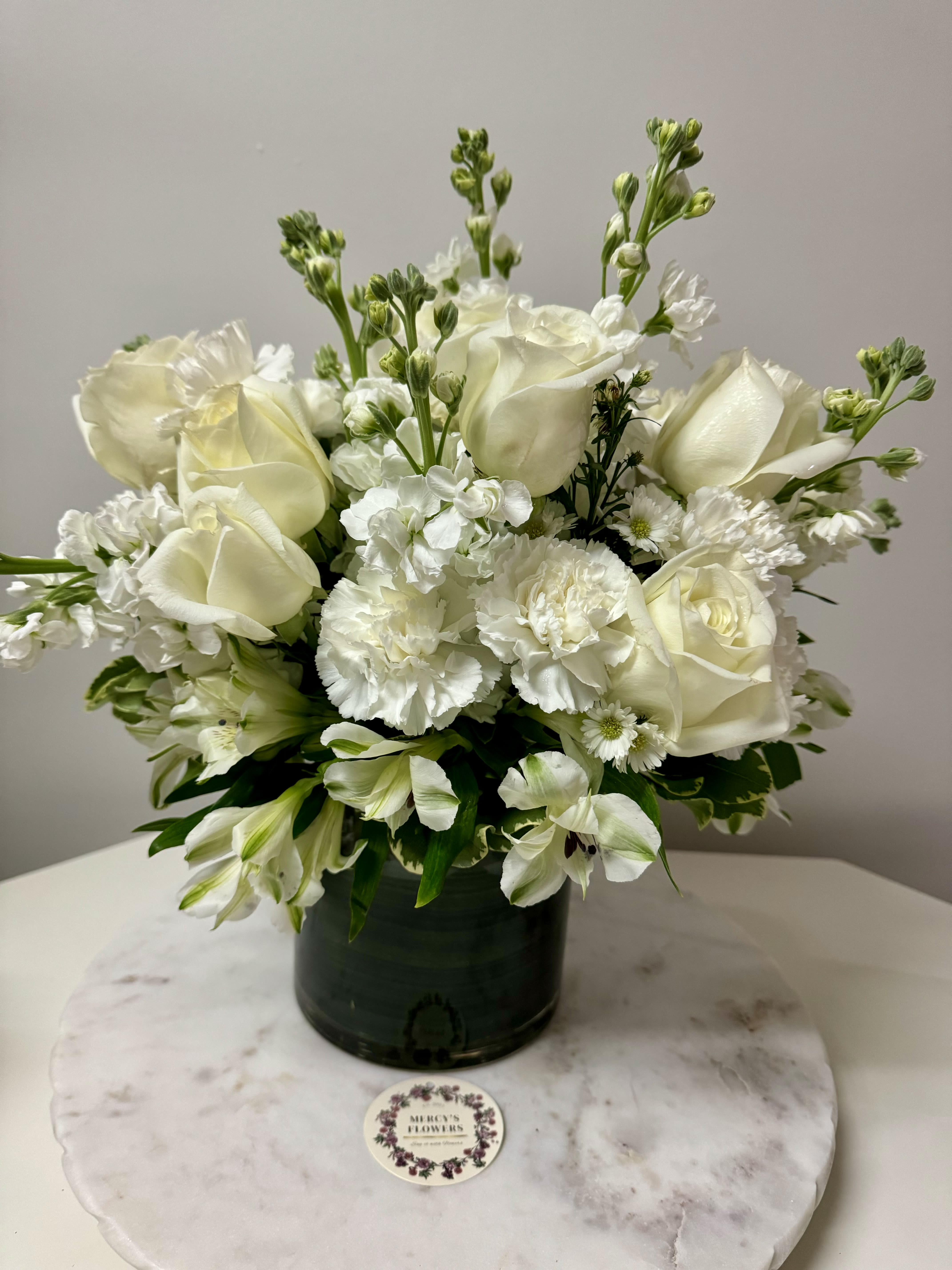 White roses and carnations arranged in a dark green vase