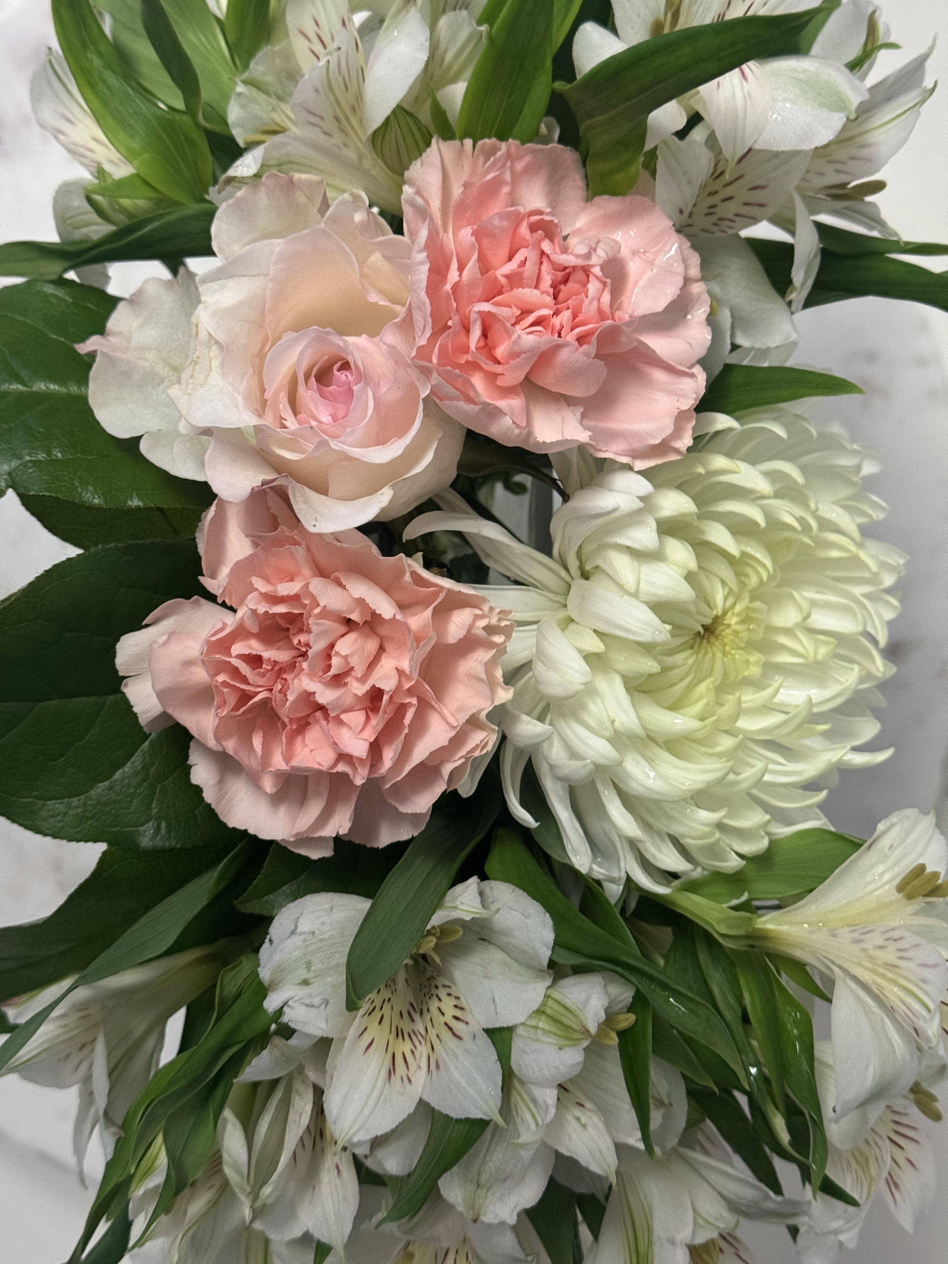 Pink carnations and white lilies with green foliage in a bouquet