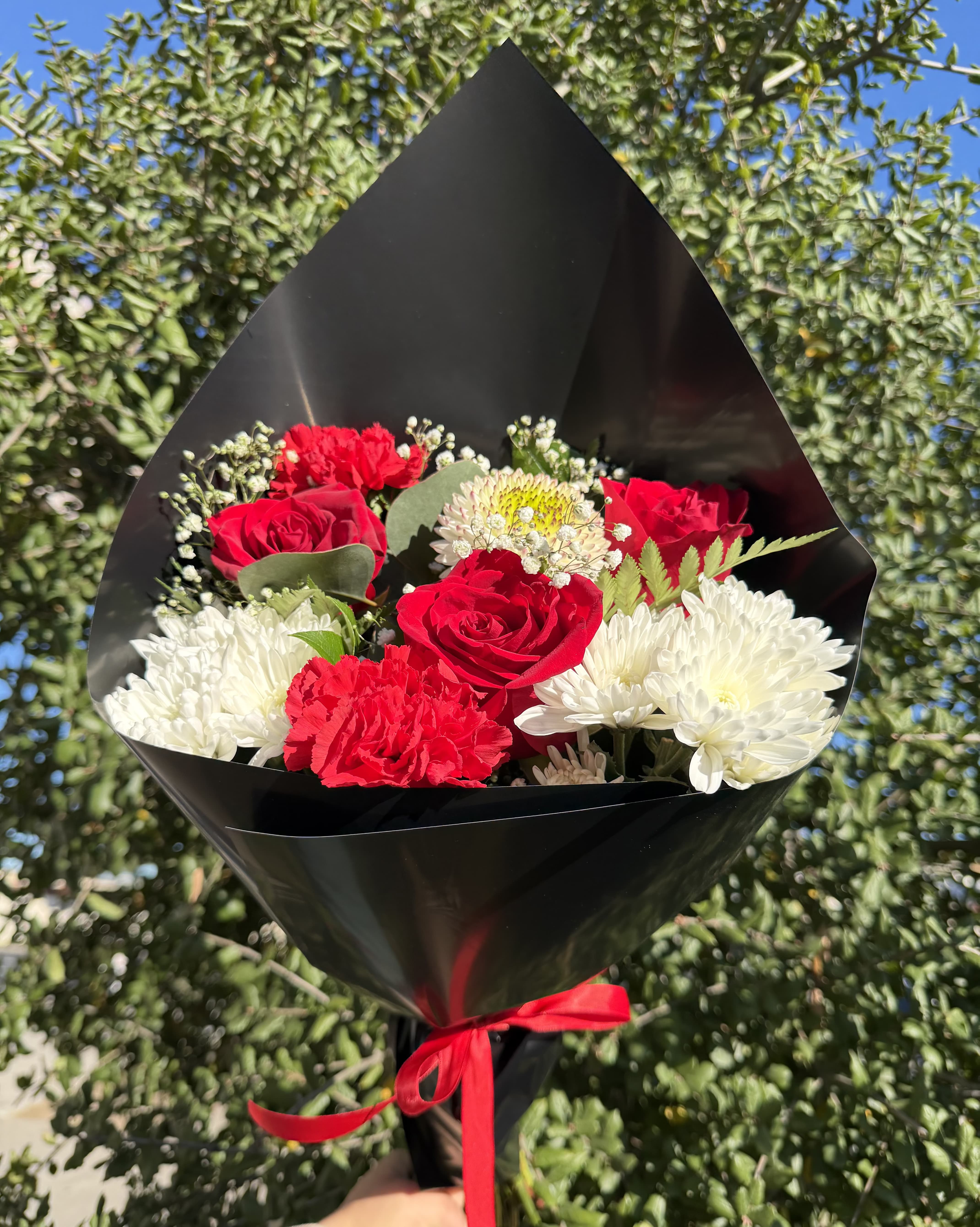 Bouquet of red roses and white chrysanthemums wrapped in black paper