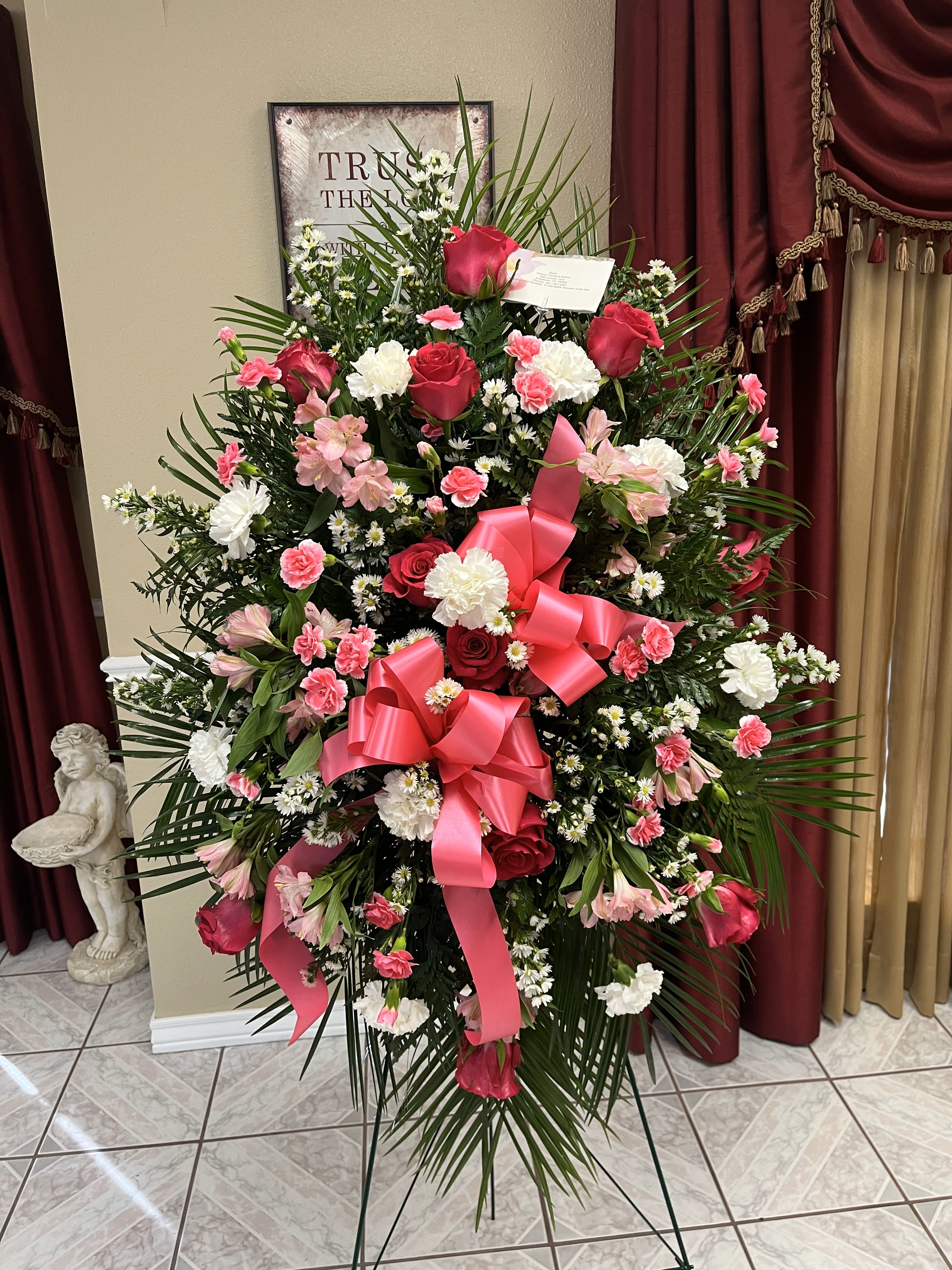 Large standing floral spray with pink and white flowers and a pink ribbon