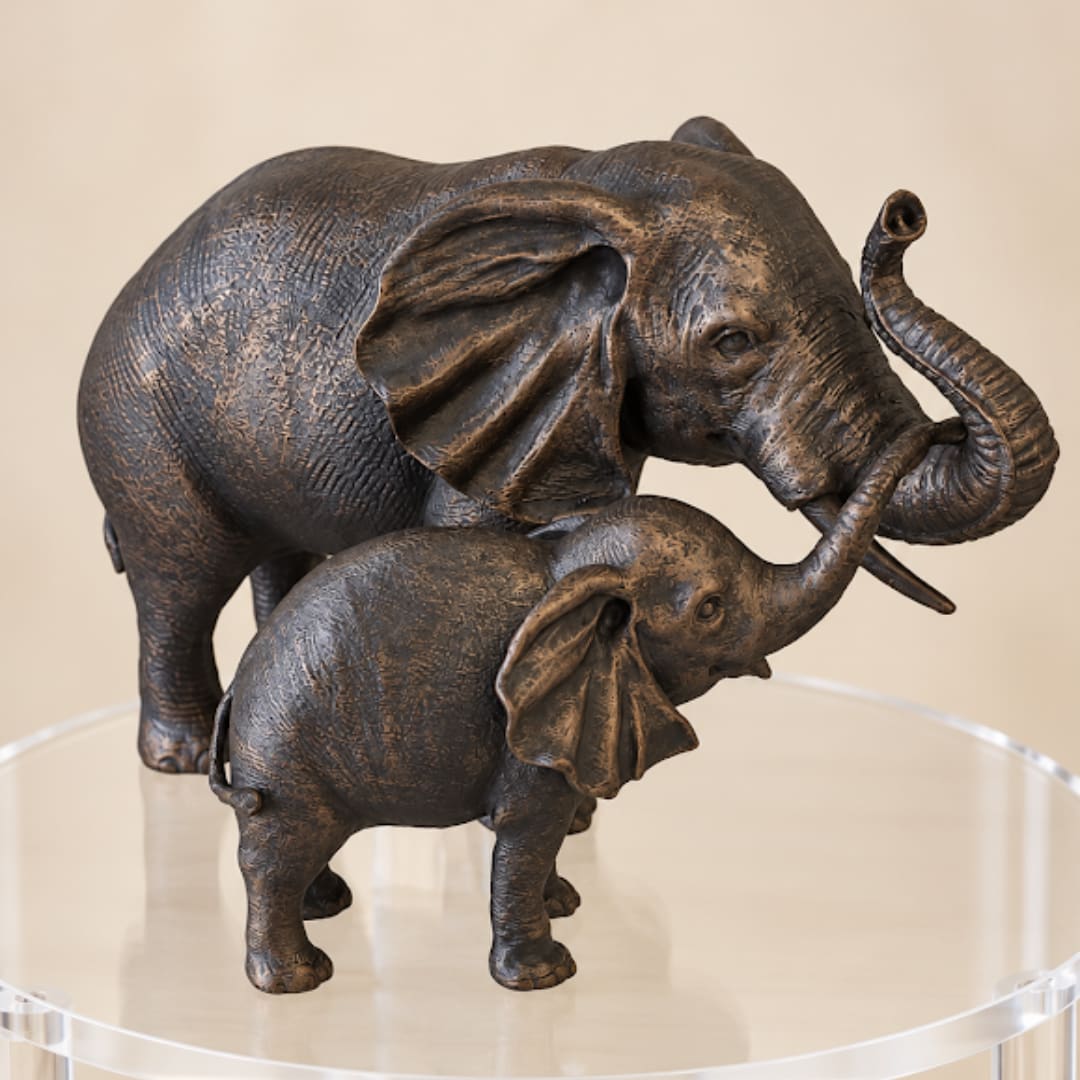 Two bronze elephant figurines on a clear round stand