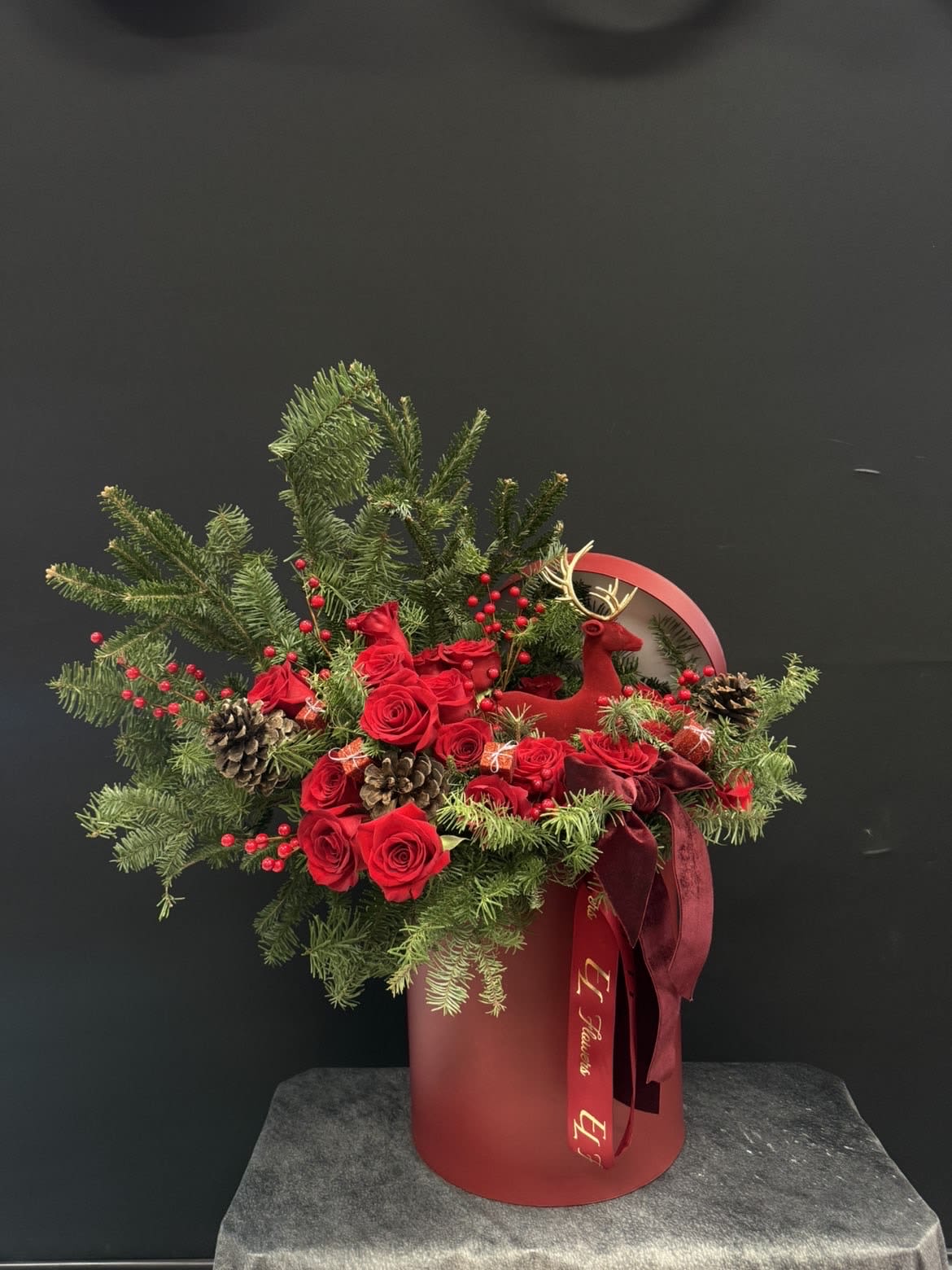Royal Christmas Luxury Arrangement - A stunning Christmas luxury arrangement featuring premium red roses, fresh winter greenery, pinecones, velvet ribbon accents, and festive berries, beautifully arranged in an elegant red designer box. Perfect for holiday gifting, Christmas parties, luxury home décor, or as a breathtaking centerpiece. Classic, rich, and unforgettable ️