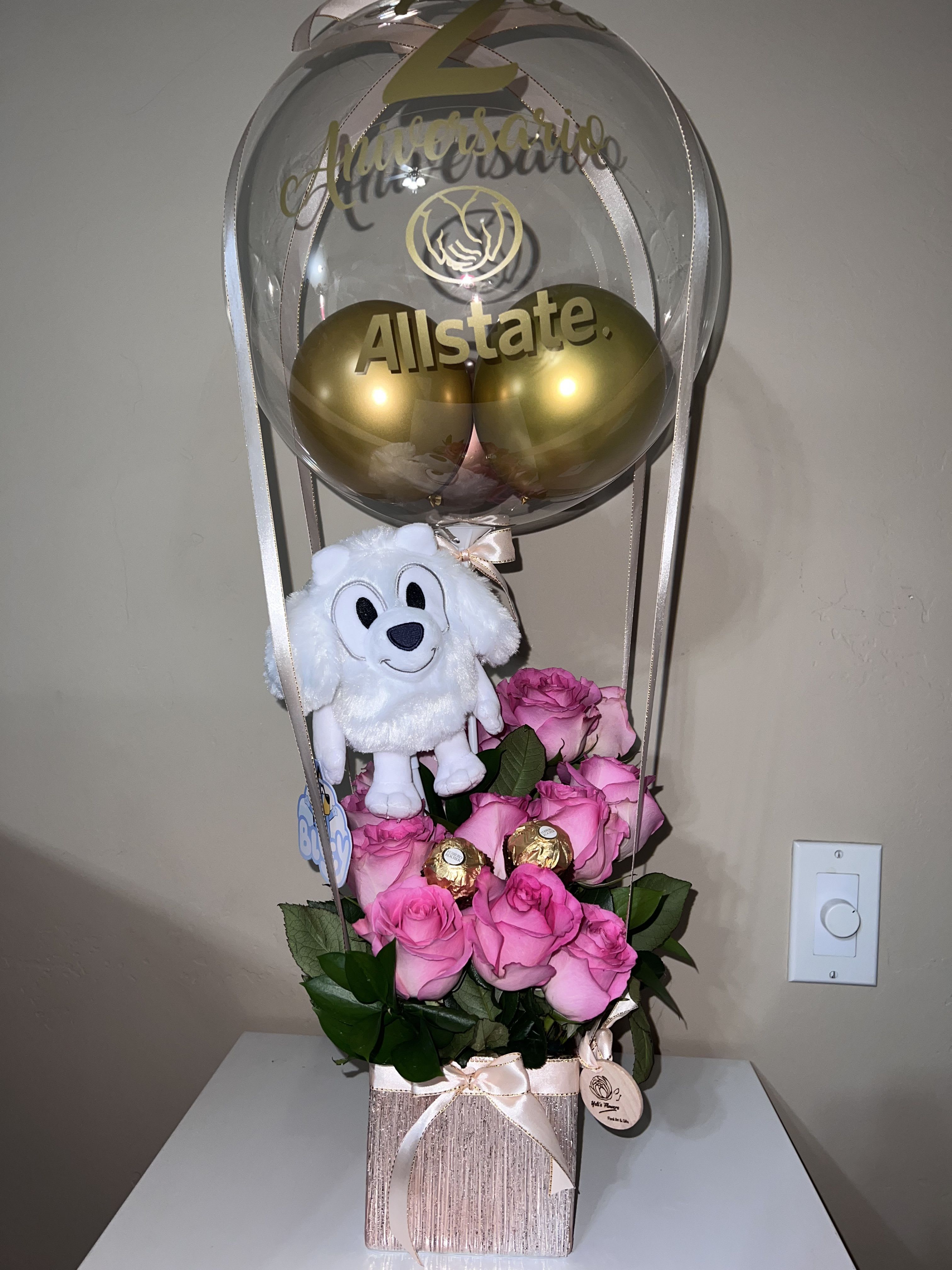 Pink roses with a plush dog and gold balloons in a clear balloon topper