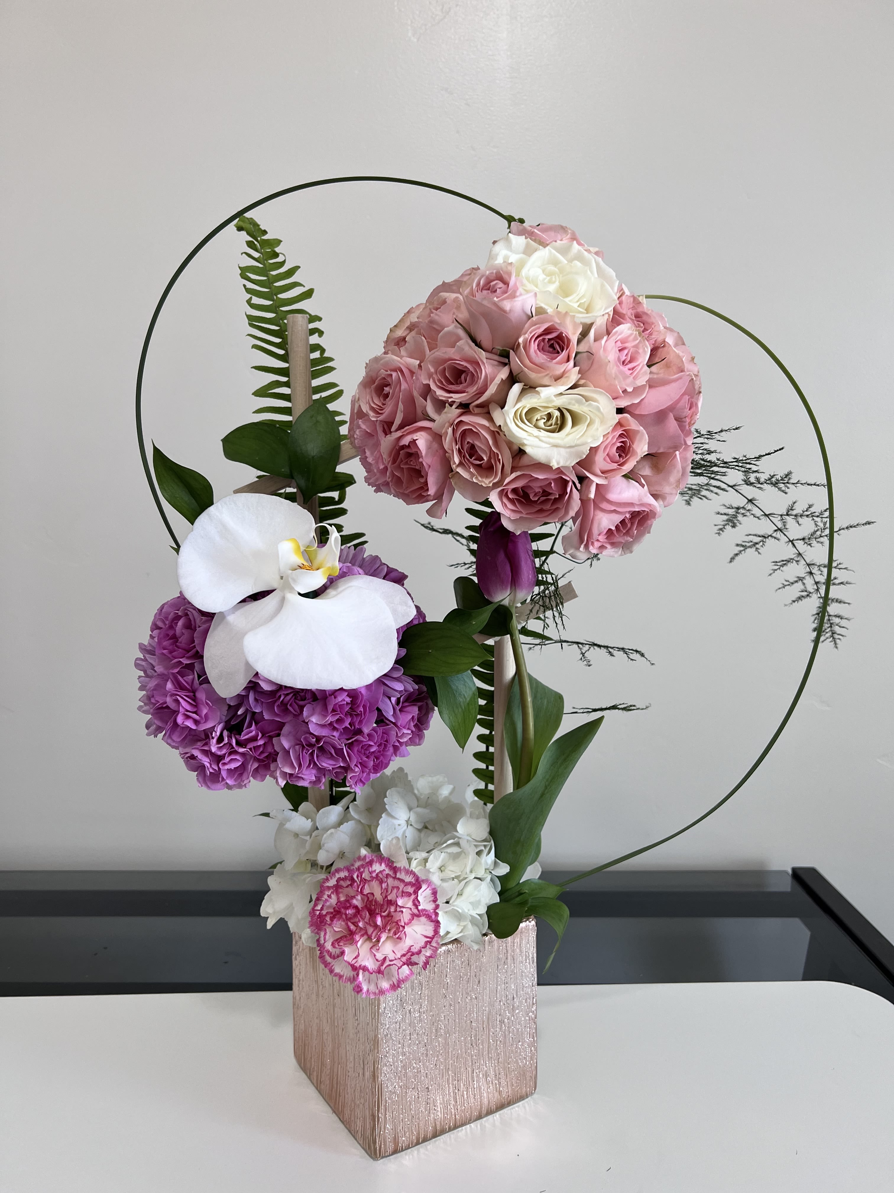 Pink and white floral arrangement in a rose-gold box with circular wire accents.