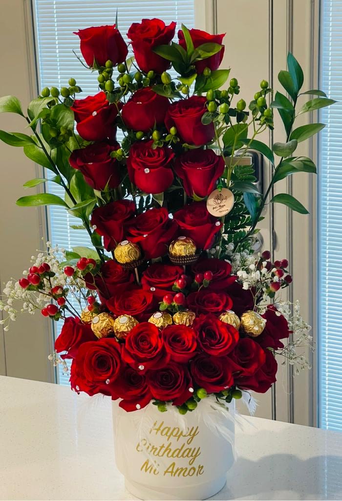 Tall arrangement of red roses in a white hatbox with gold lettering
