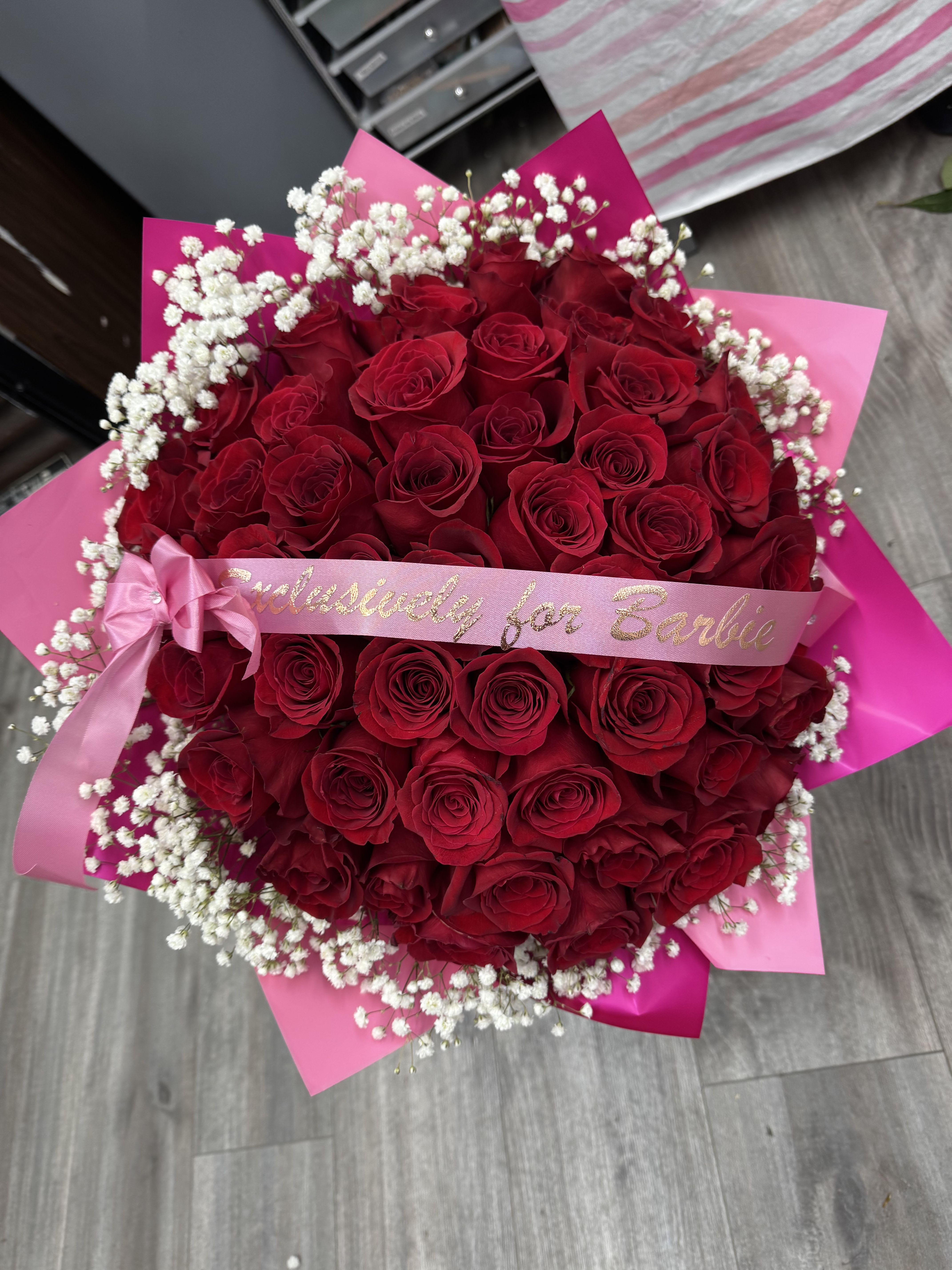 Large bouquet of red roses with white baby's breath and pink ribbon