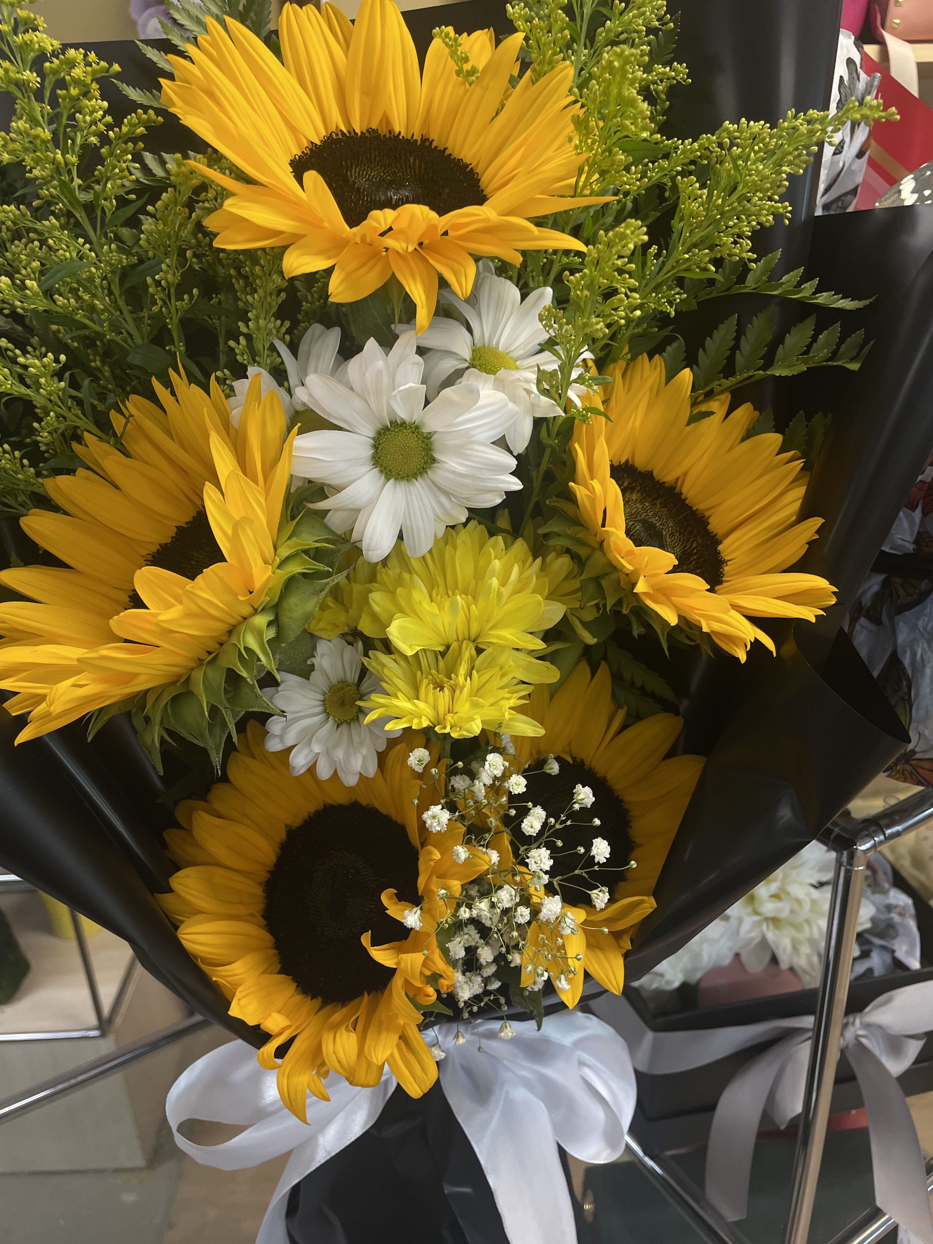 Bouquet of sunflowers and white daisies wrapped in black paper