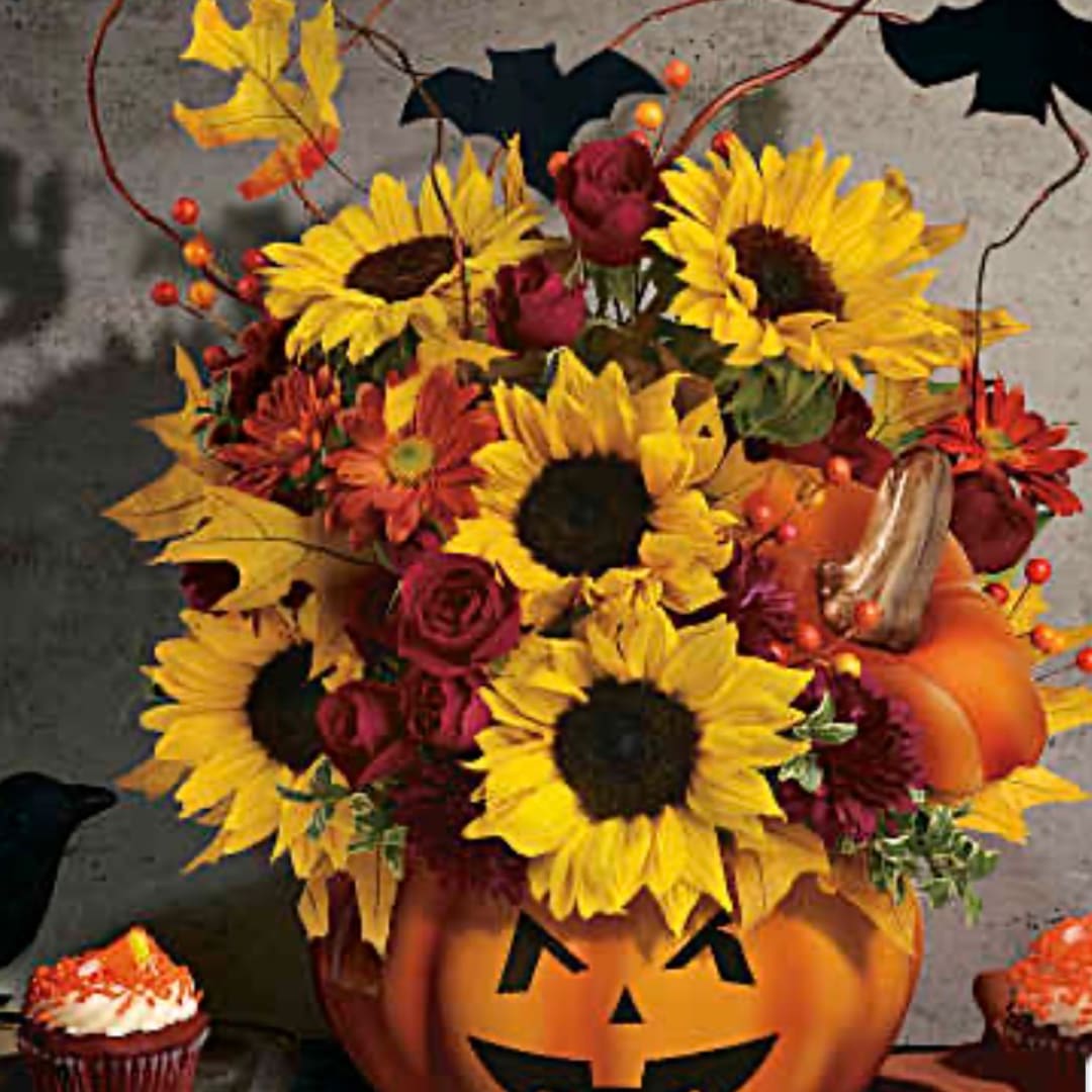 Sunflower and rose arrangement in a carved pumpkin container with Halloween accents