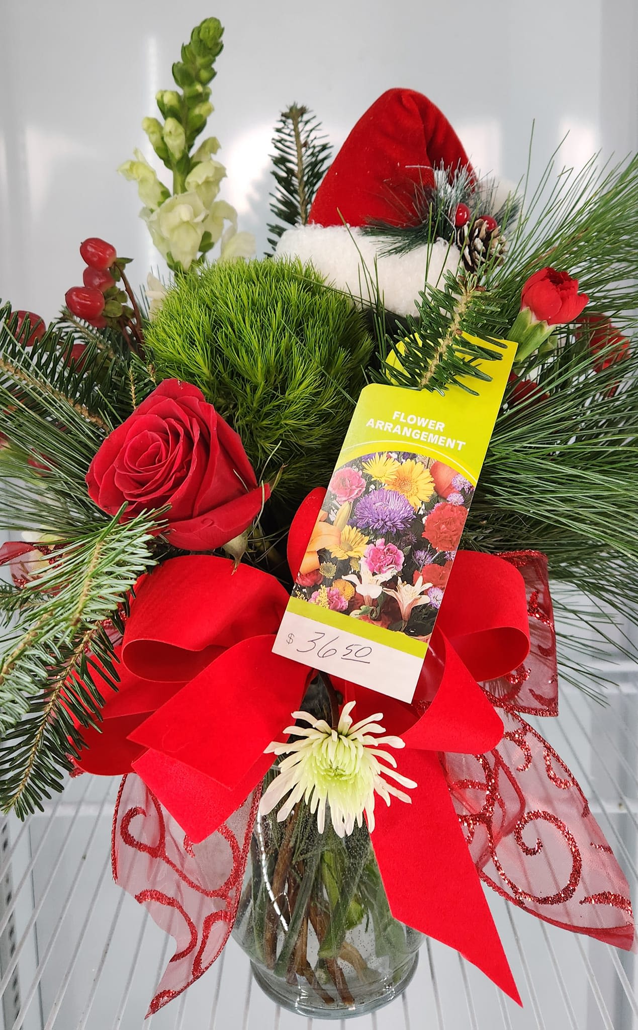 Santa's Hat - Holiday Vase arrangement with traditional flowers topped off with a Santa hat.