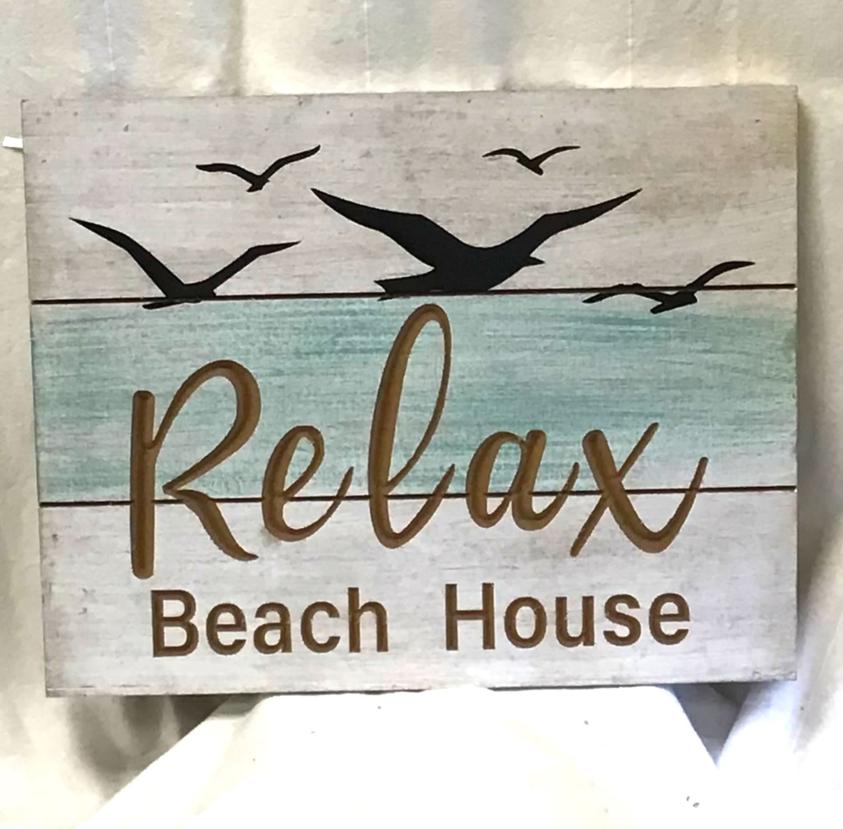 Wooden sign reading Relax Beach House with bird silhouettes