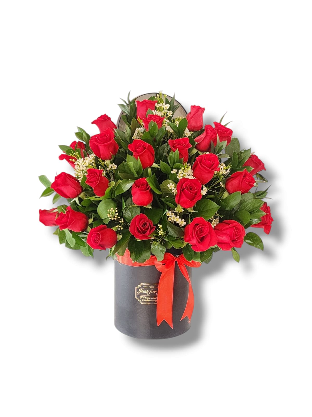 Red roses arranged in a black hatbox with a red ribbon