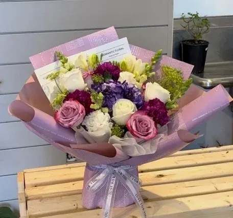 Bouquet of pink, white, and purple flowers wrapped in lavender paper