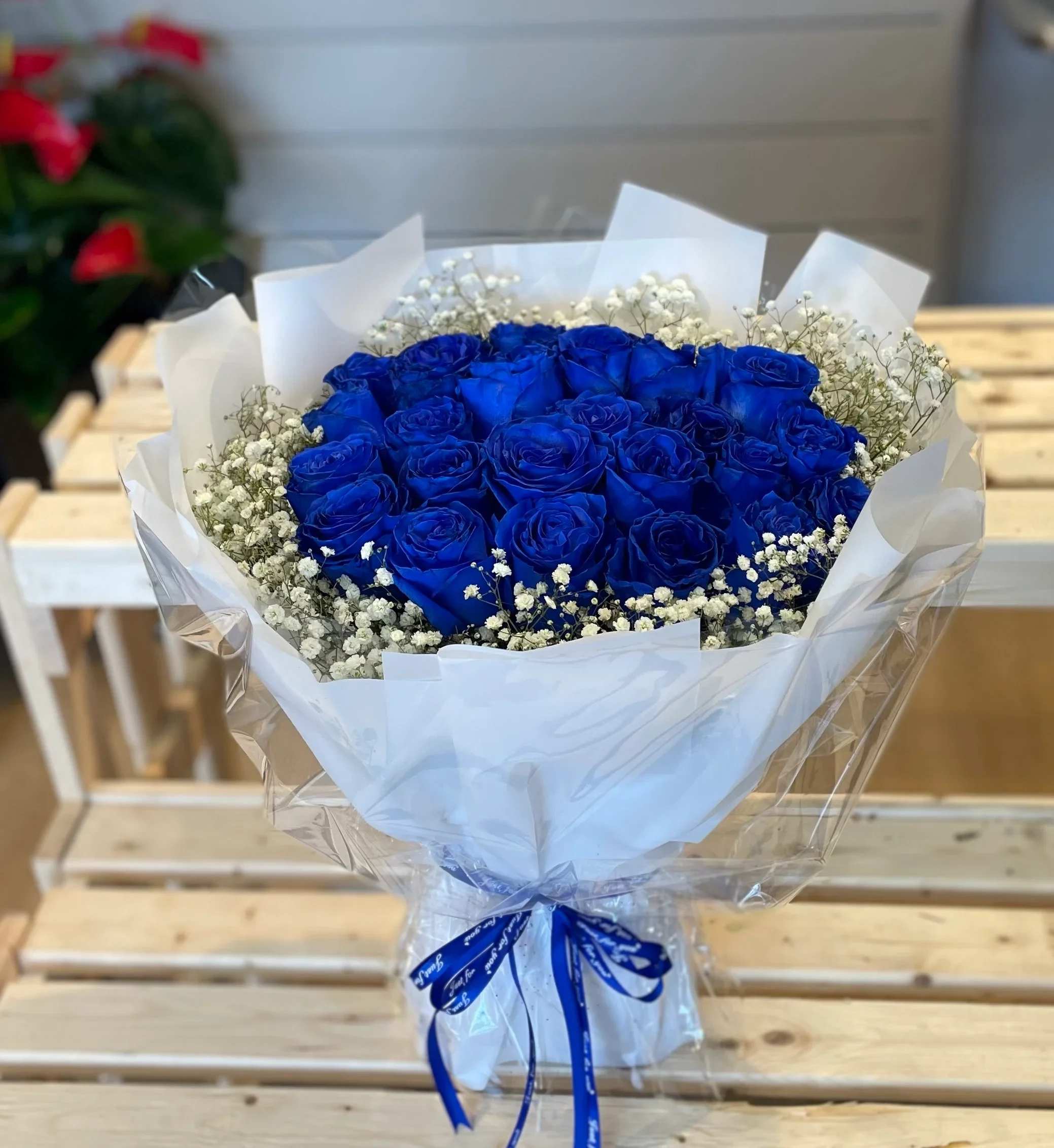 Bouquet of vivid blue roses with white baby's breath in white wrapping