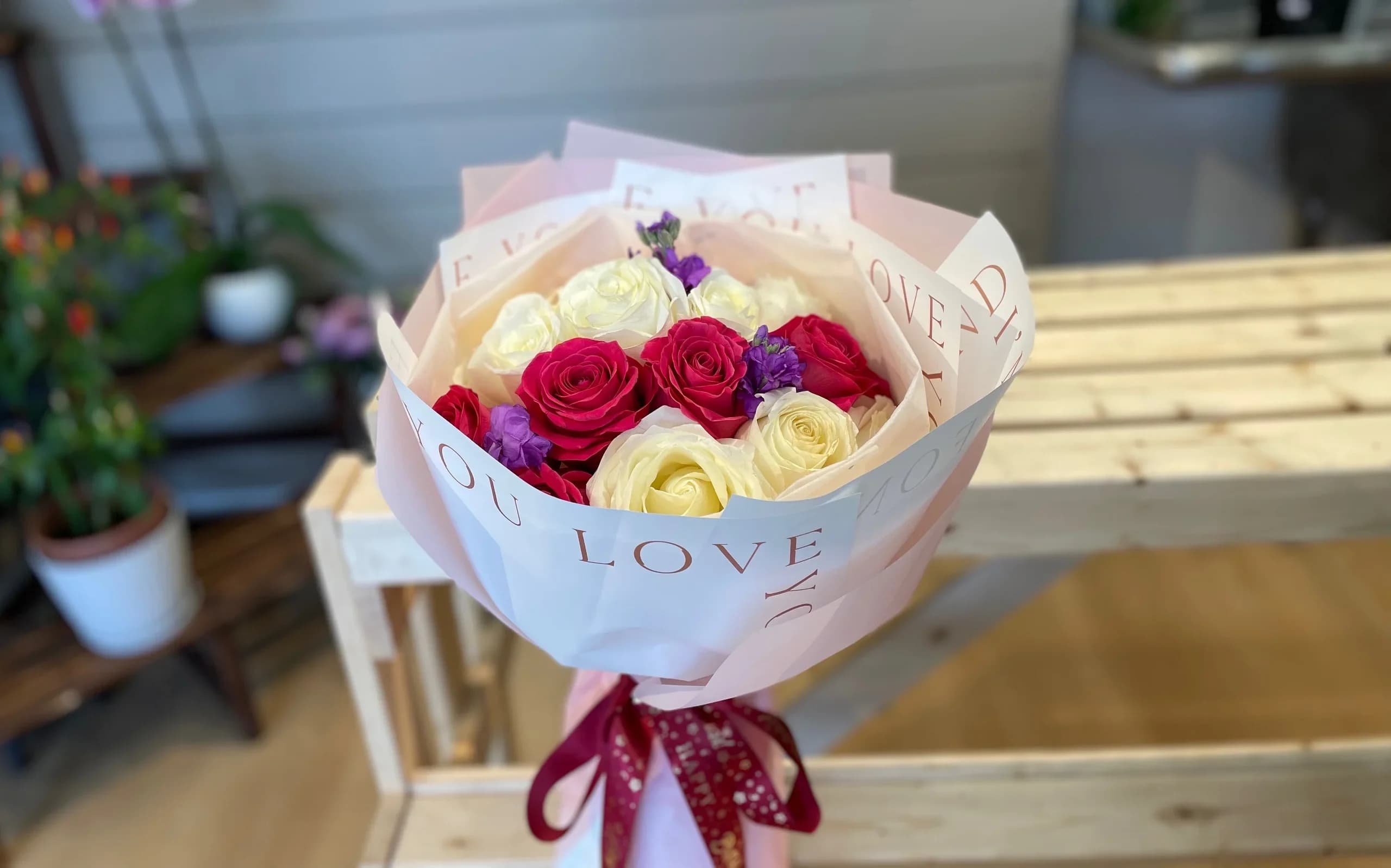 Bouquet of pink, white, and purple roses wrapped in paper