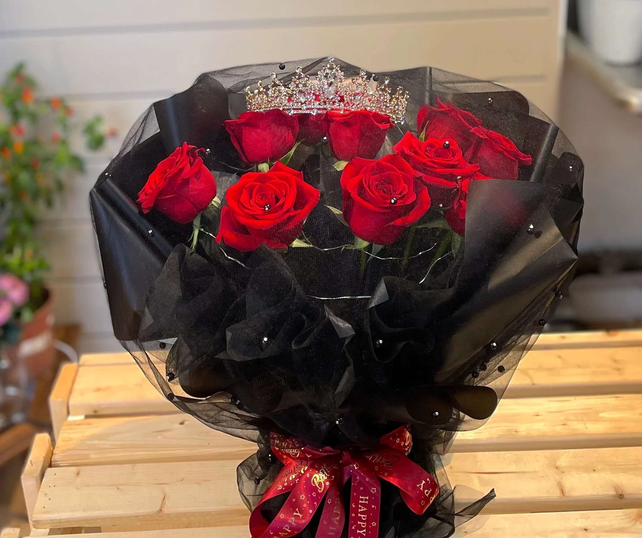 Bouquet of red roses wrapped in black mesh with a jeweled crown topper