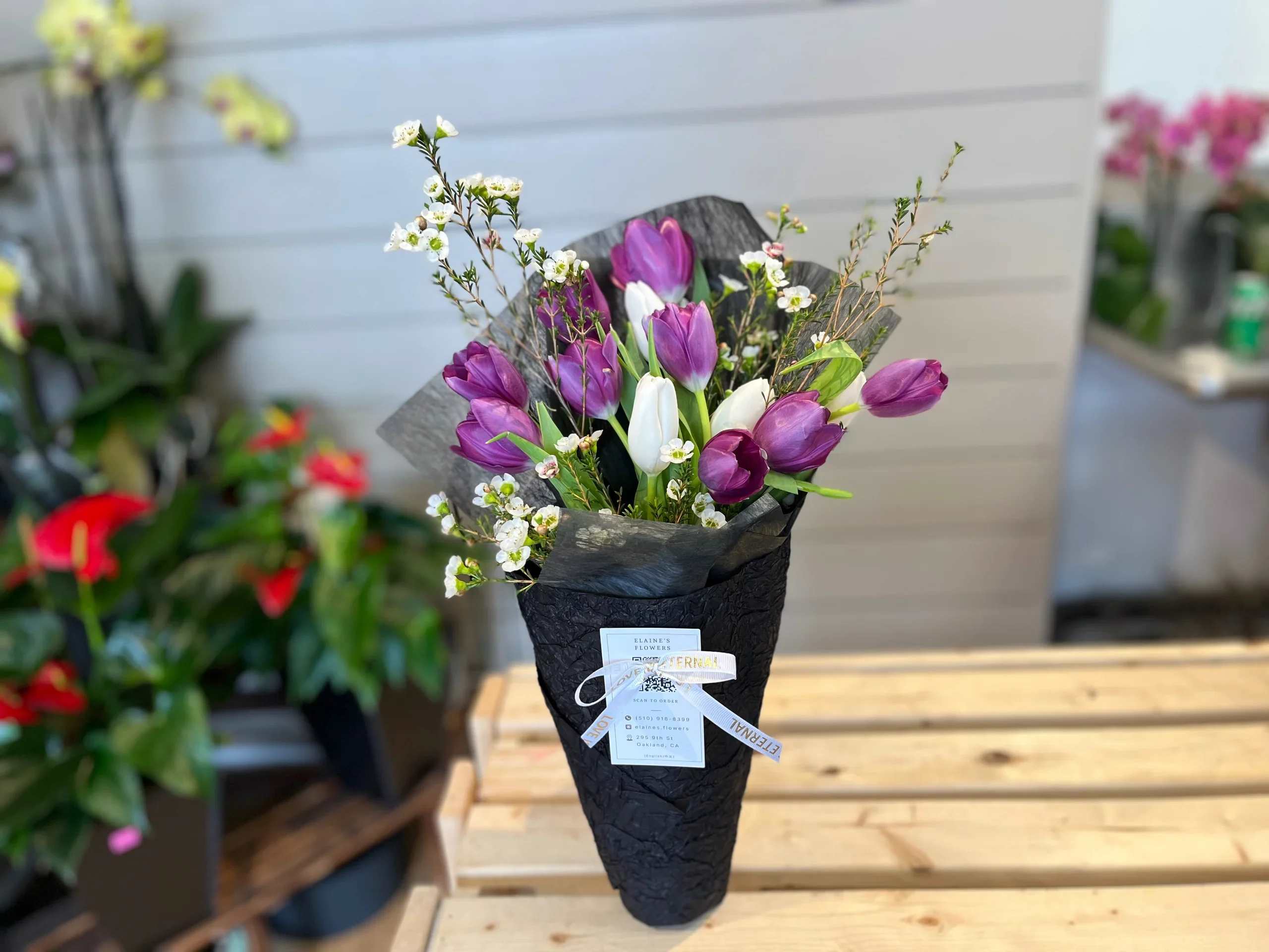 Purple and white tulips in black wrap with small white blossoms