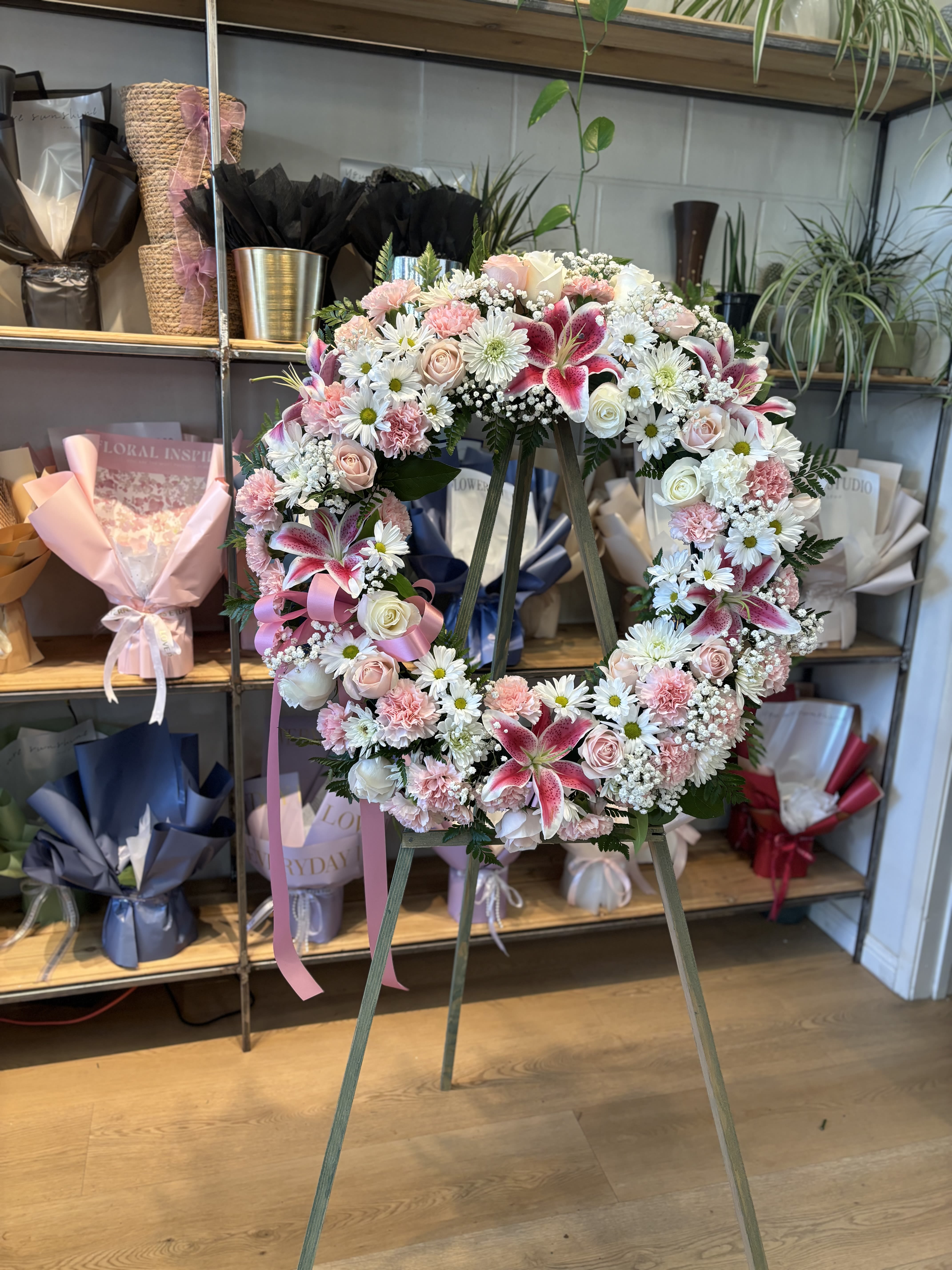 Heart-shaped floral wreath on an easel with pink and white flowers