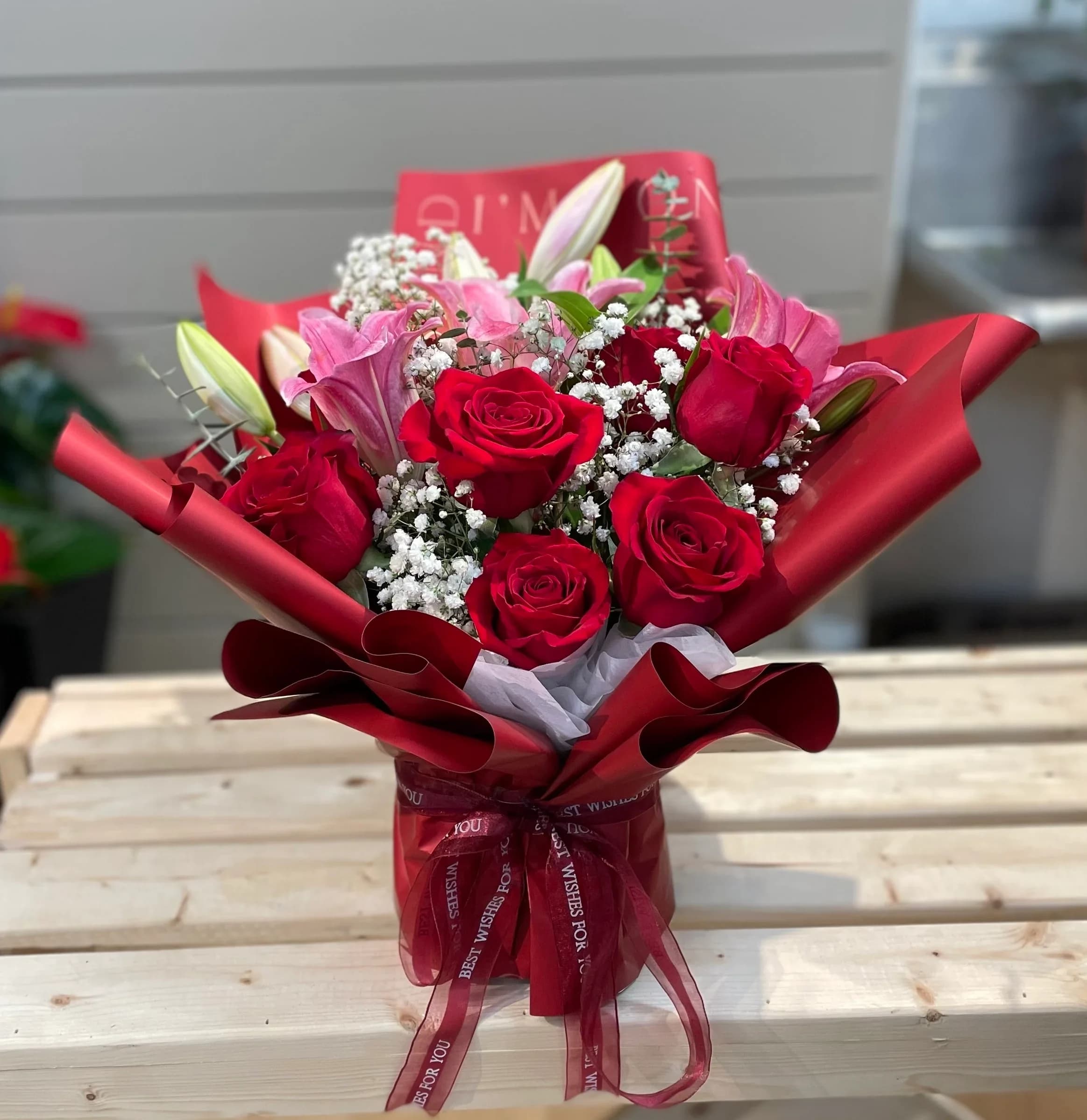 Bouquet of red roses and pink lilies wrapped in red paper