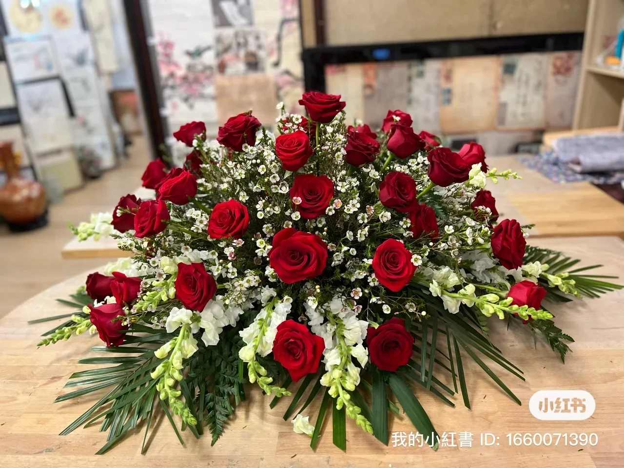 Low arrangement of red roses and white filler flowers on a table