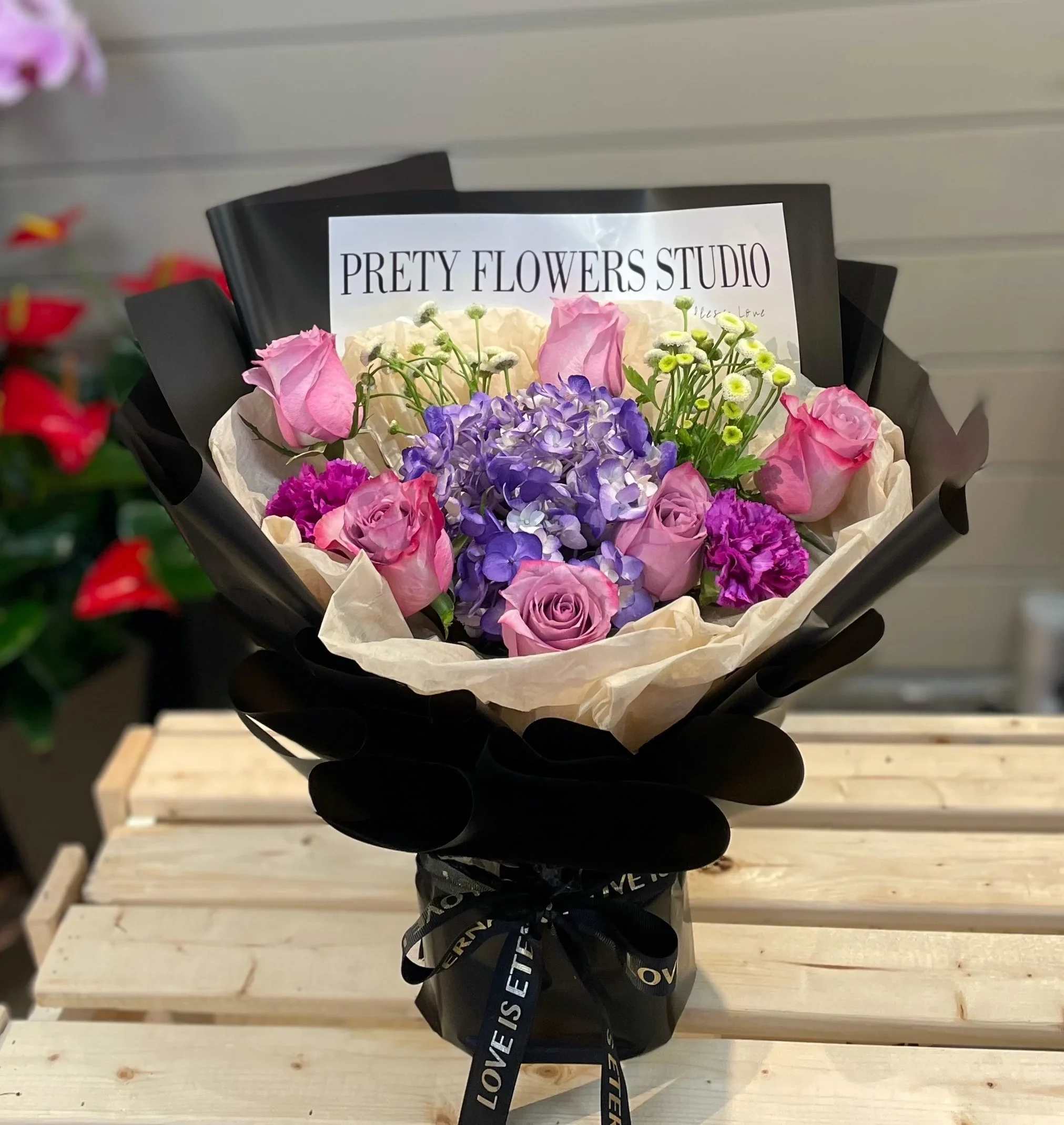 Bouquet of pink roses and purple hydrangea in black wrapping