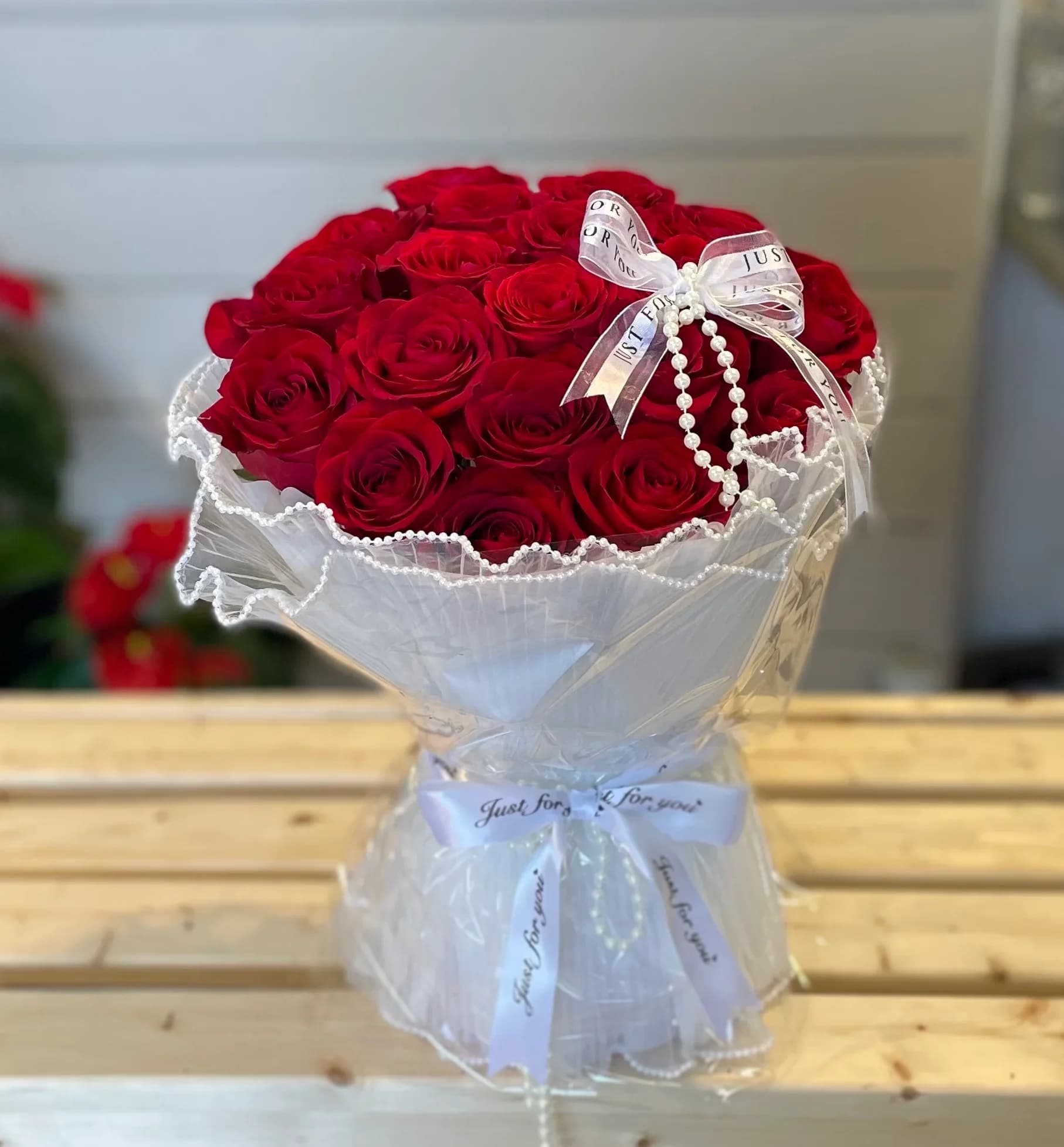 Bouquet of red roses wrapped in white paper with a ribbon