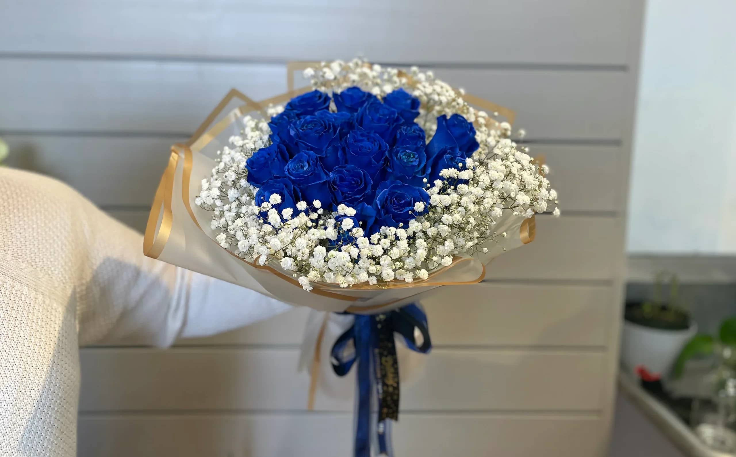 Bouquet of vivid blue roses with white baby's breath and gold-edged wrap