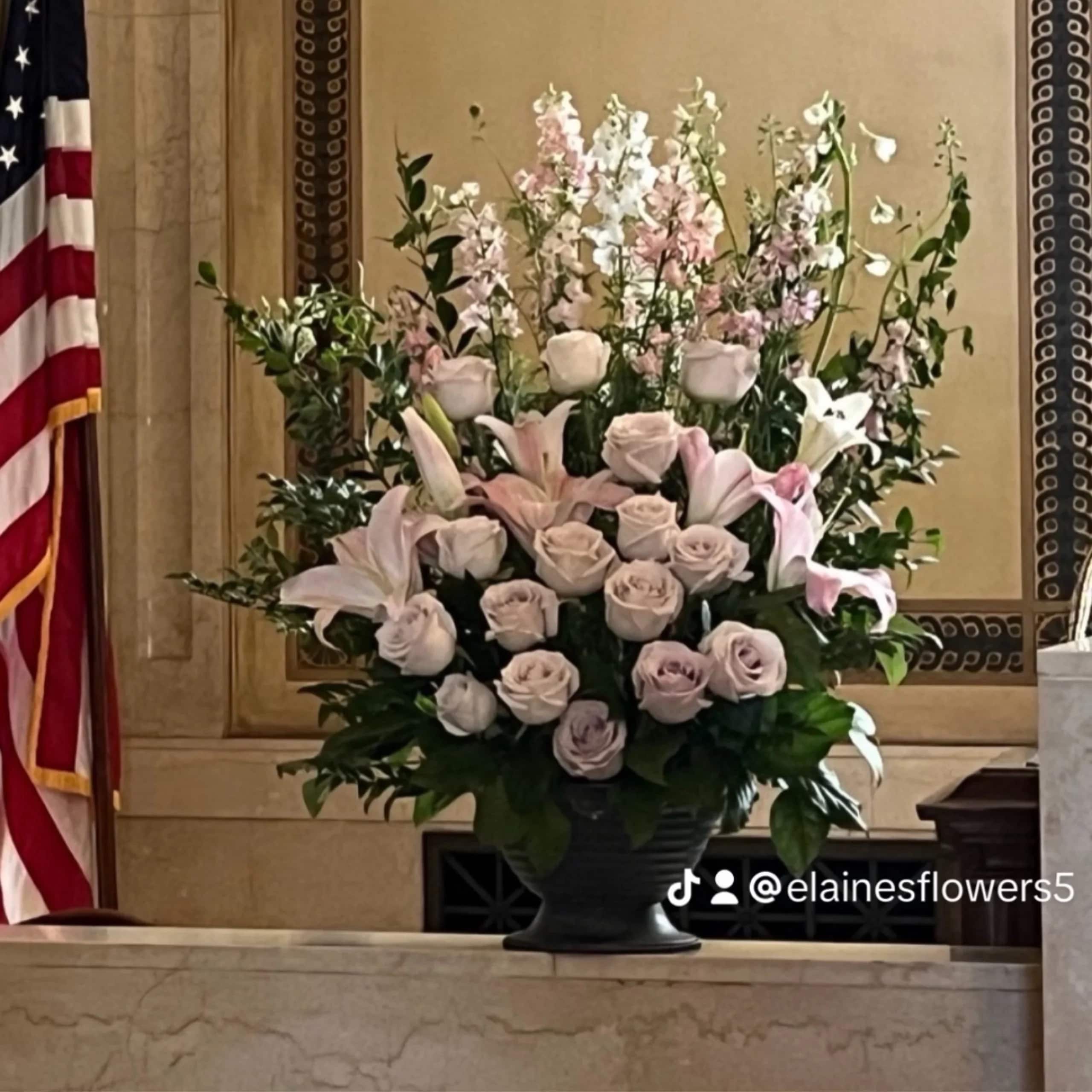 Large pastel floral arrangement in a dark urn vase
