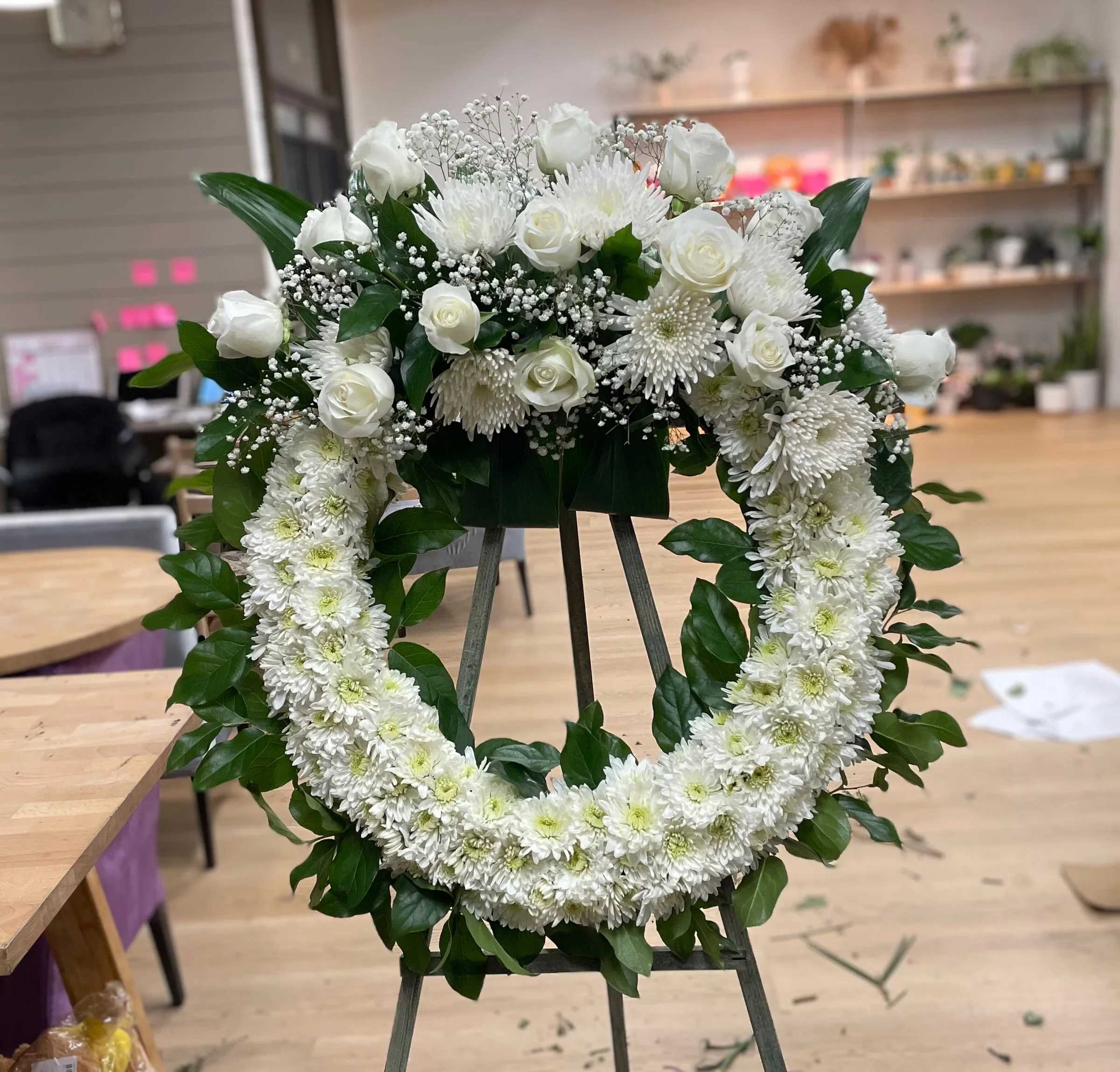 White floral wreath on an easel with roses and chrysanthemums