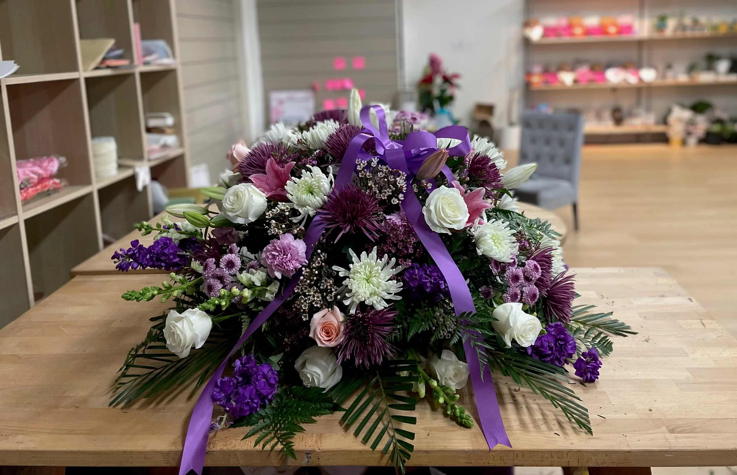 Purple and white floral spray with ribbon on a table
