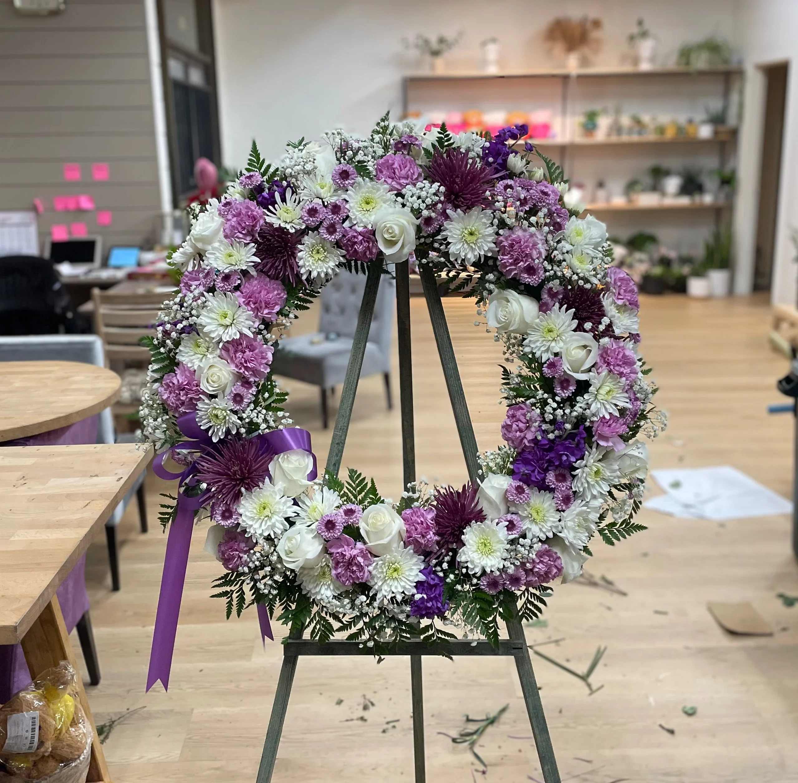 Purple and white floral wreath on an easel with a ribbon