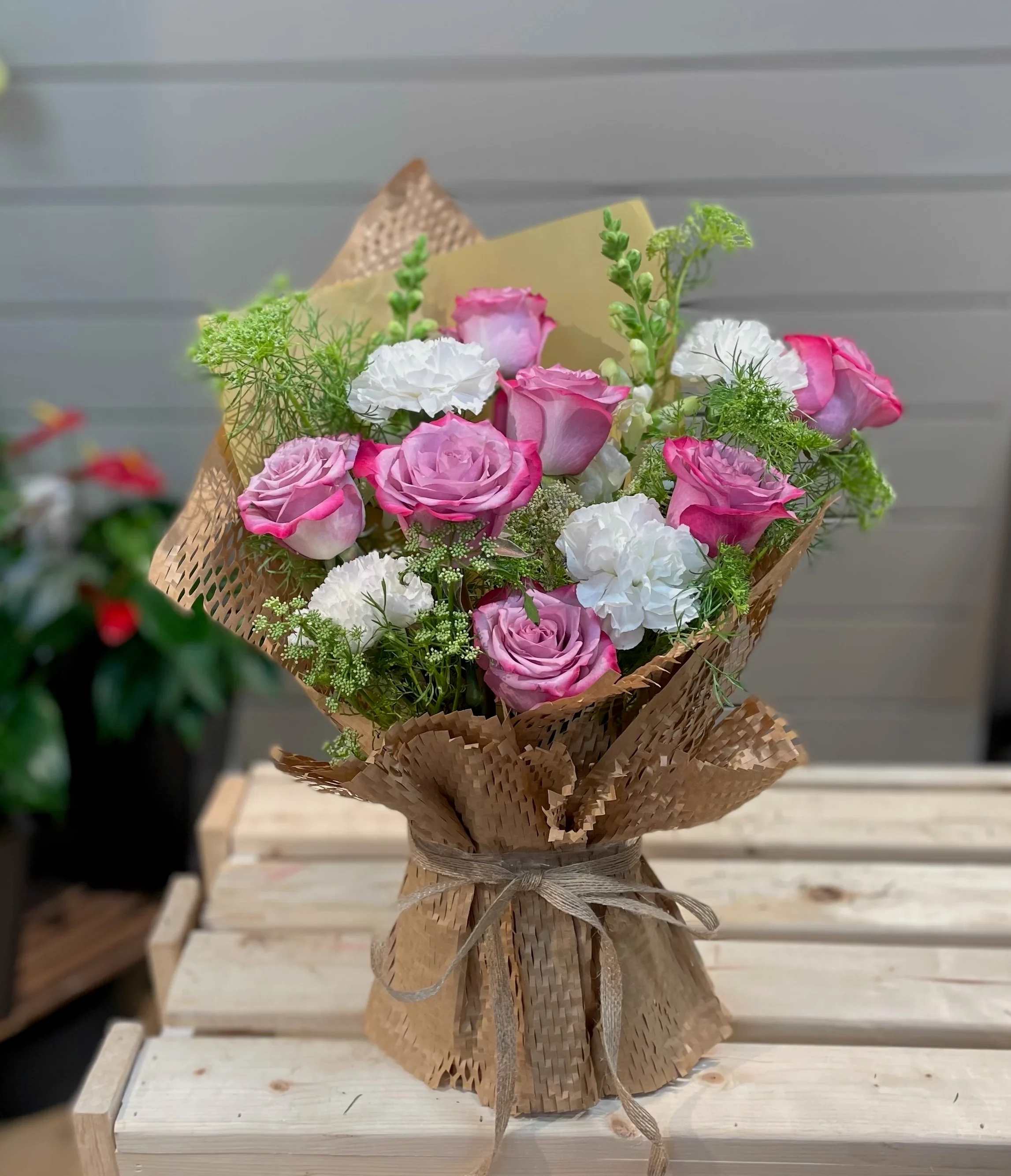 Pink and white roses arranged in brown paper wrapping