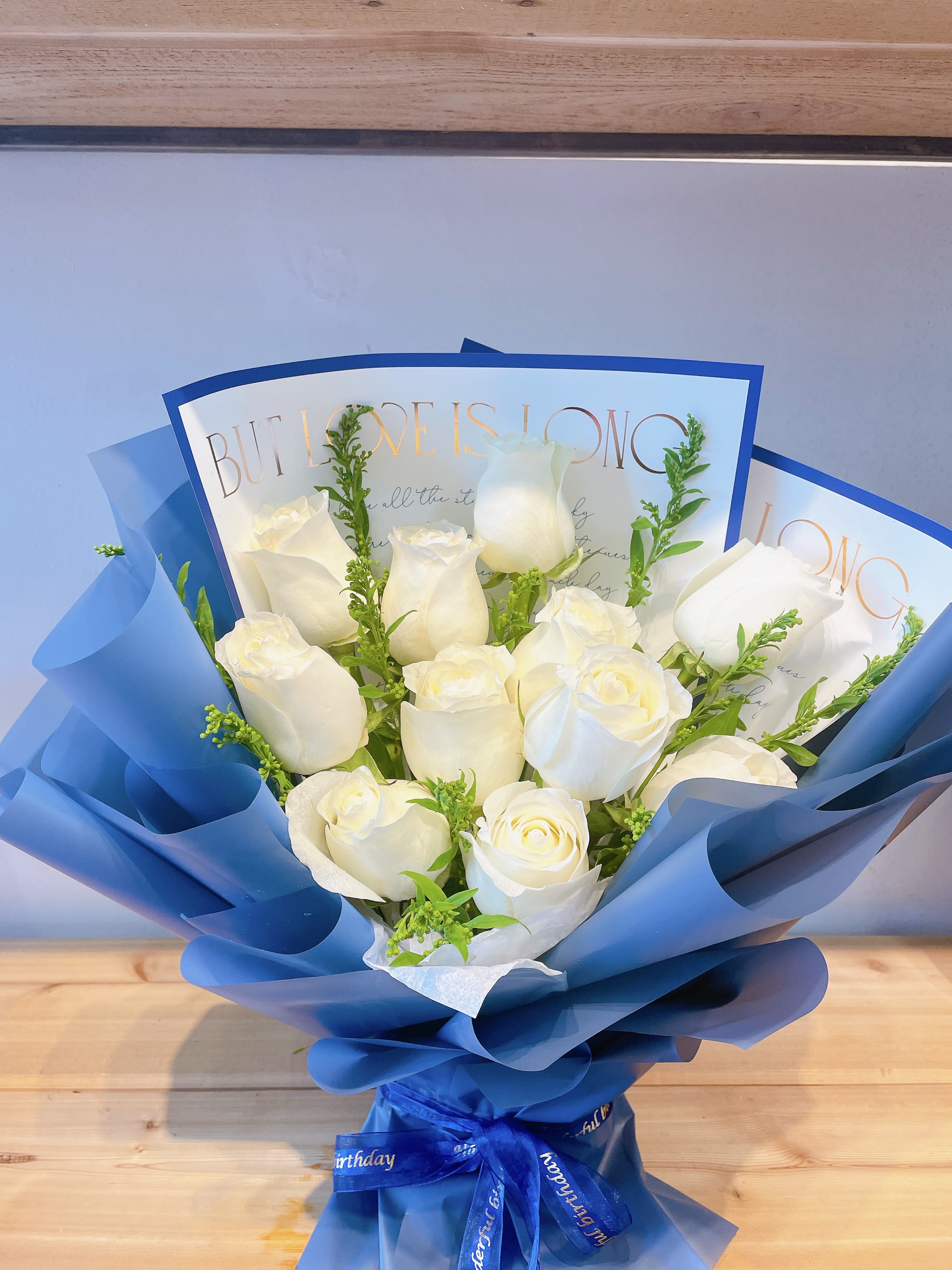 Bouquet of white roses wrapped in blue paper with a ribbon