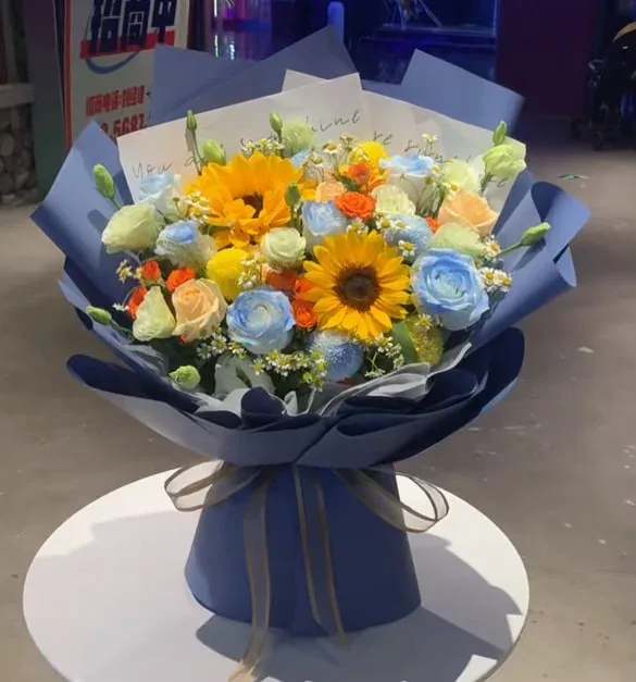 Bouquet of sunflowers and pastel roses wrapped in blue paper
