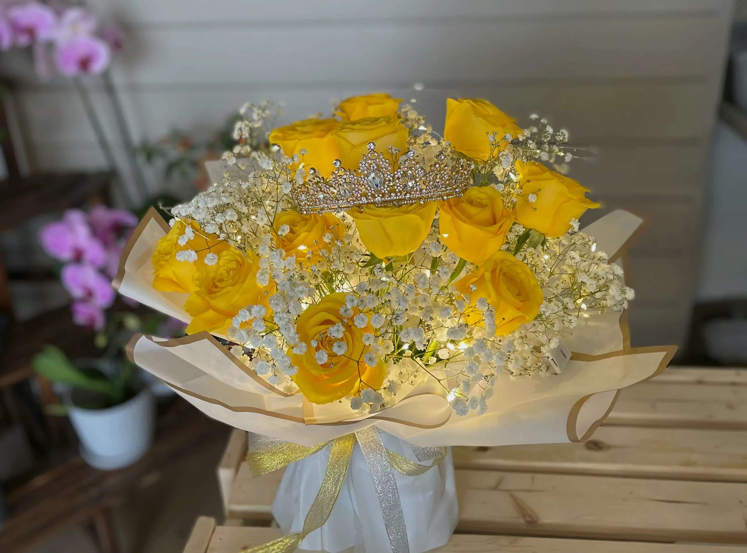 Yellow roses with baby's breath and a jeweled tiara in wrapped bouquet
