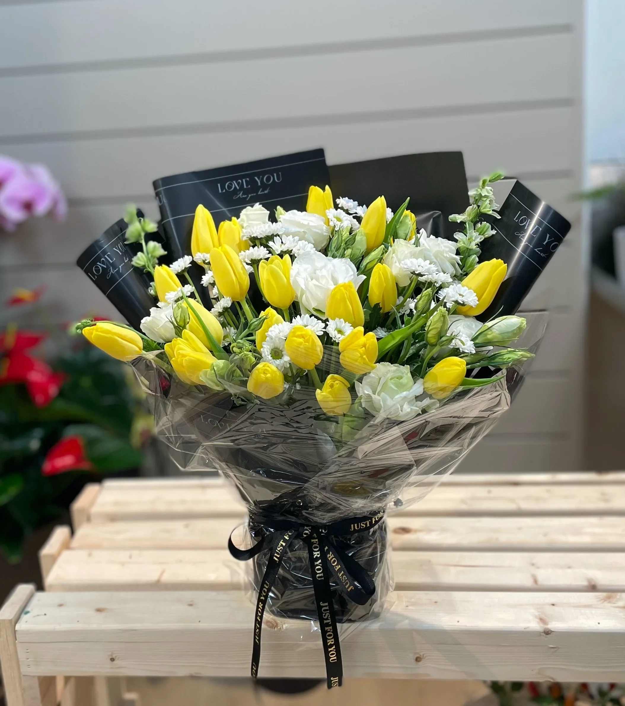 Bouquet of yellow tulips and white flowers wrapped in black paper
