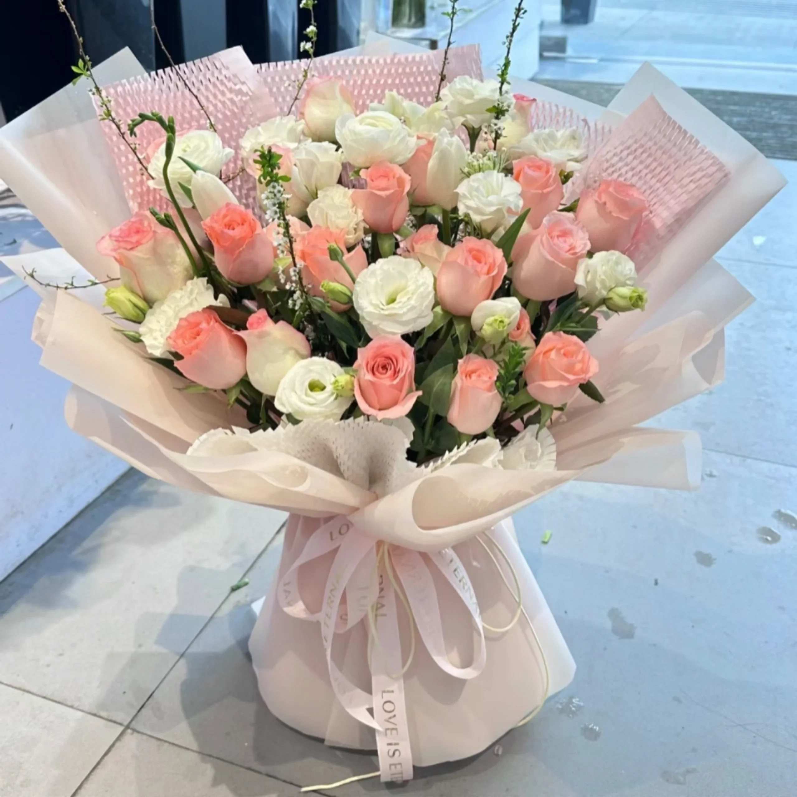 Bouquet of pink and white roses with ribbon in a wrapped presentation