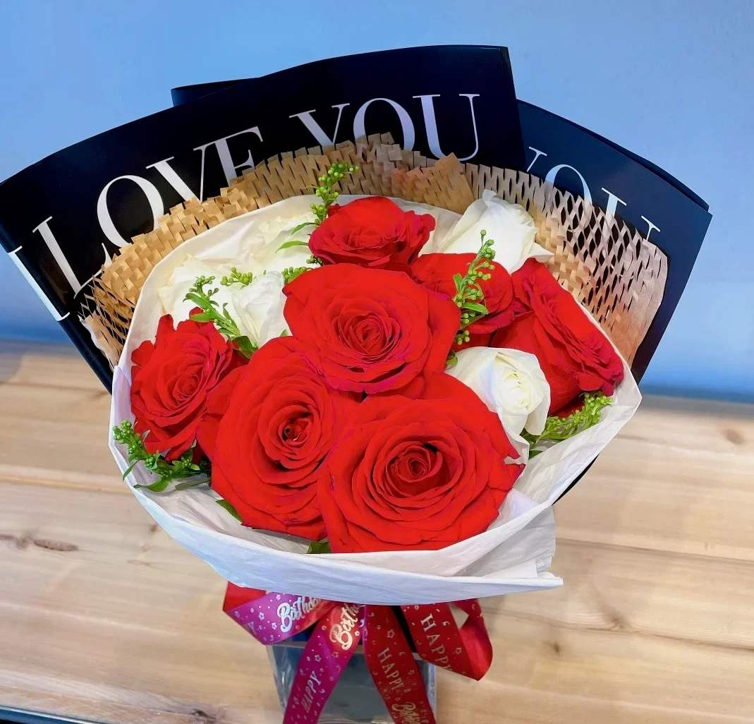 Bouquet of red and white roses wrapped in paper with a ribbon