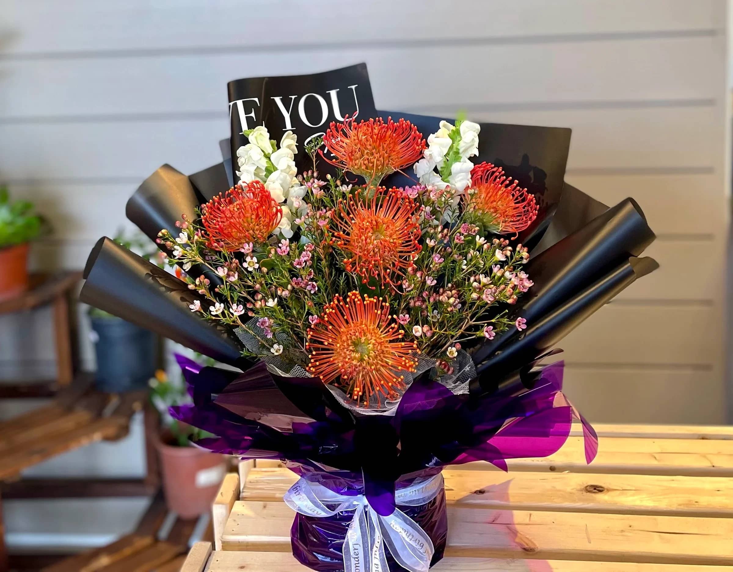 Bouquet of orange pincushion flowers with white blooms and purple wrapping