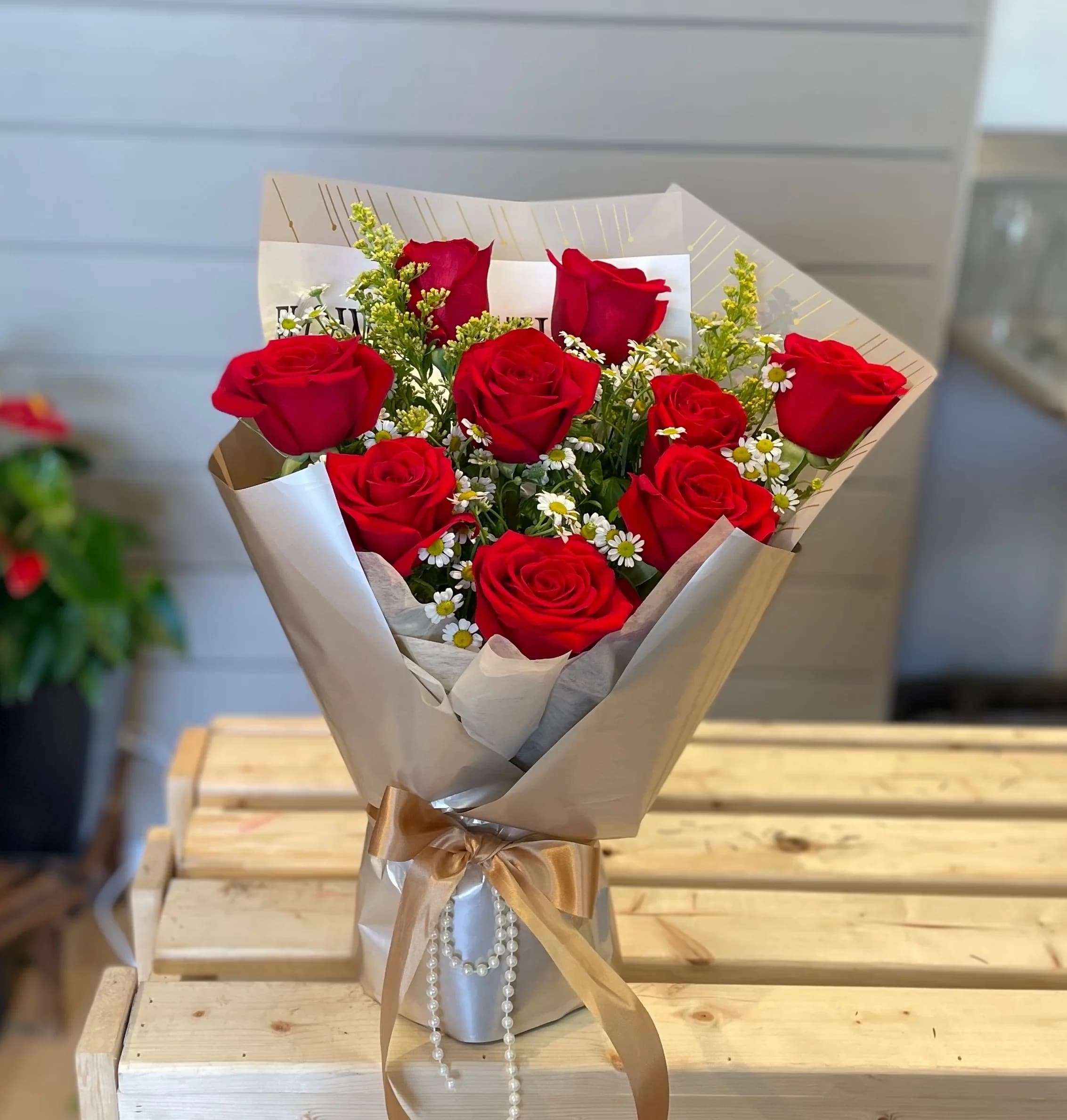 Bouquet of red roses with small white daisies in beige wrapping