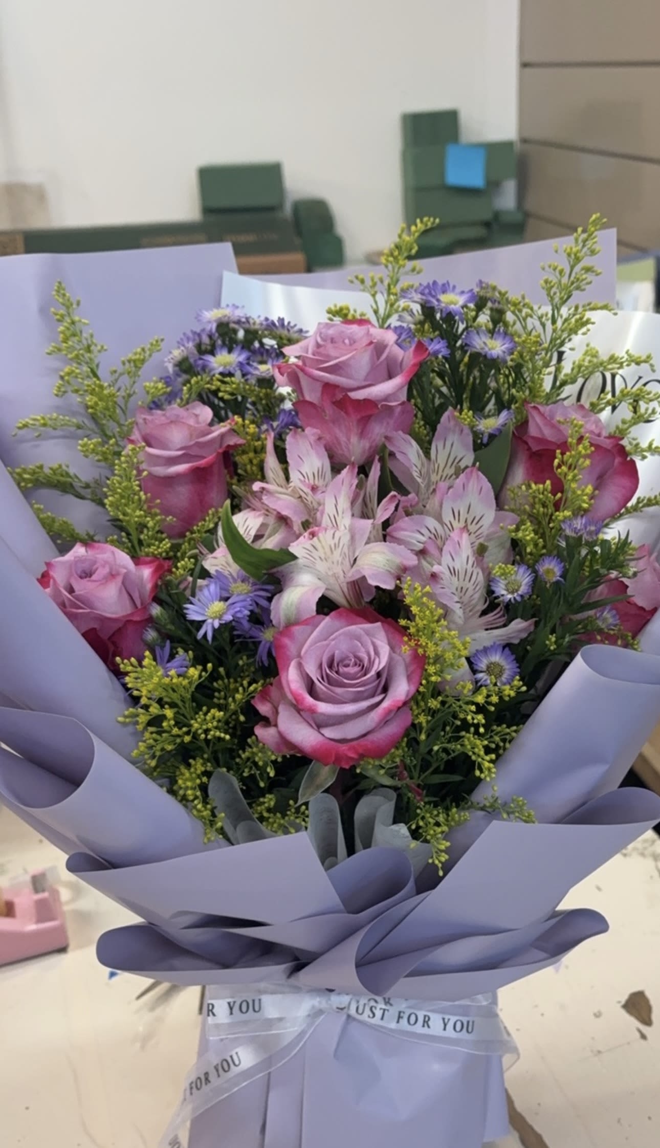 Bouquet of pink roses and purple flowers wrapped in lavender paper