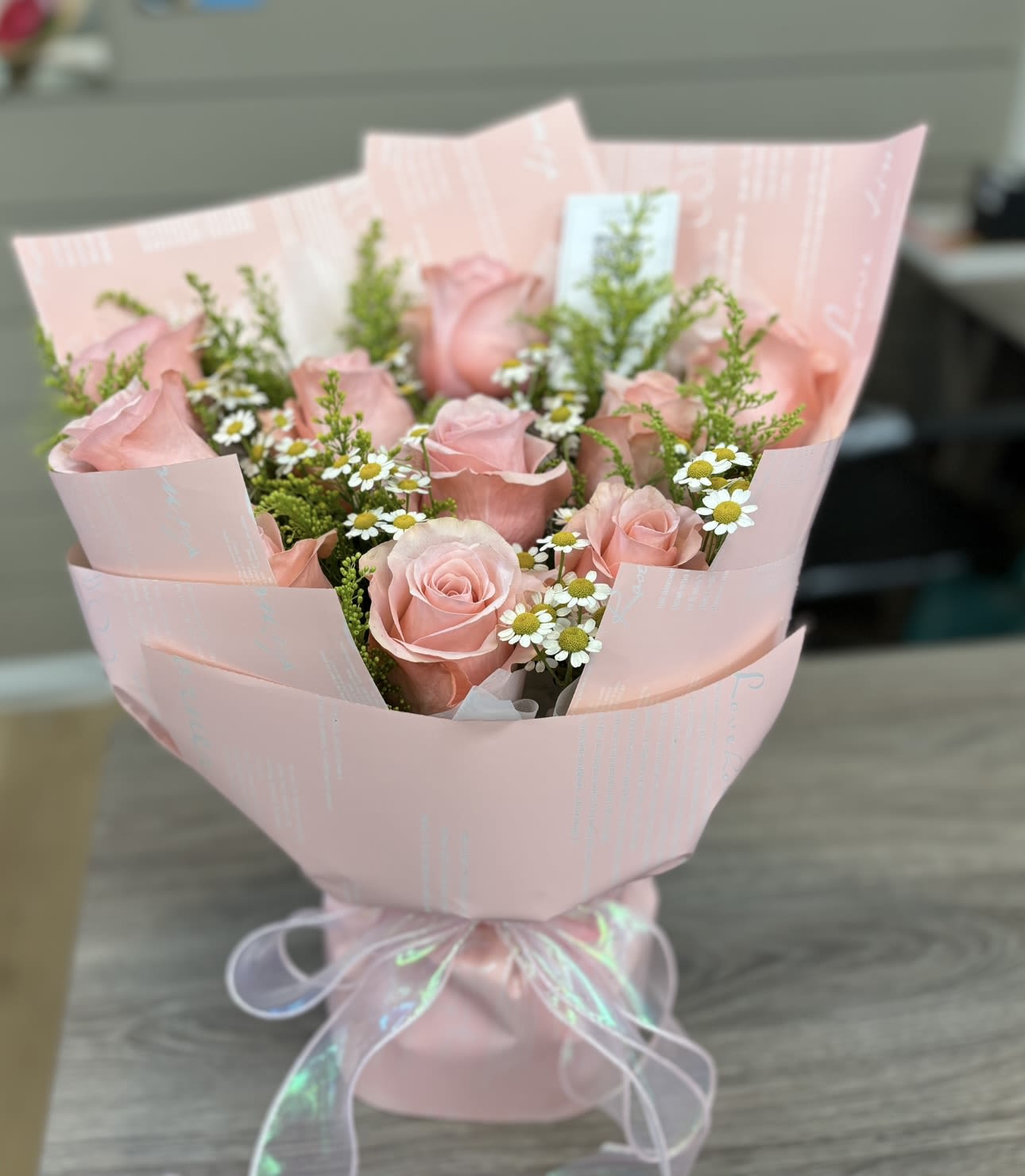 Pink rose bouquet with small white daisies wrapped in pale pink paper