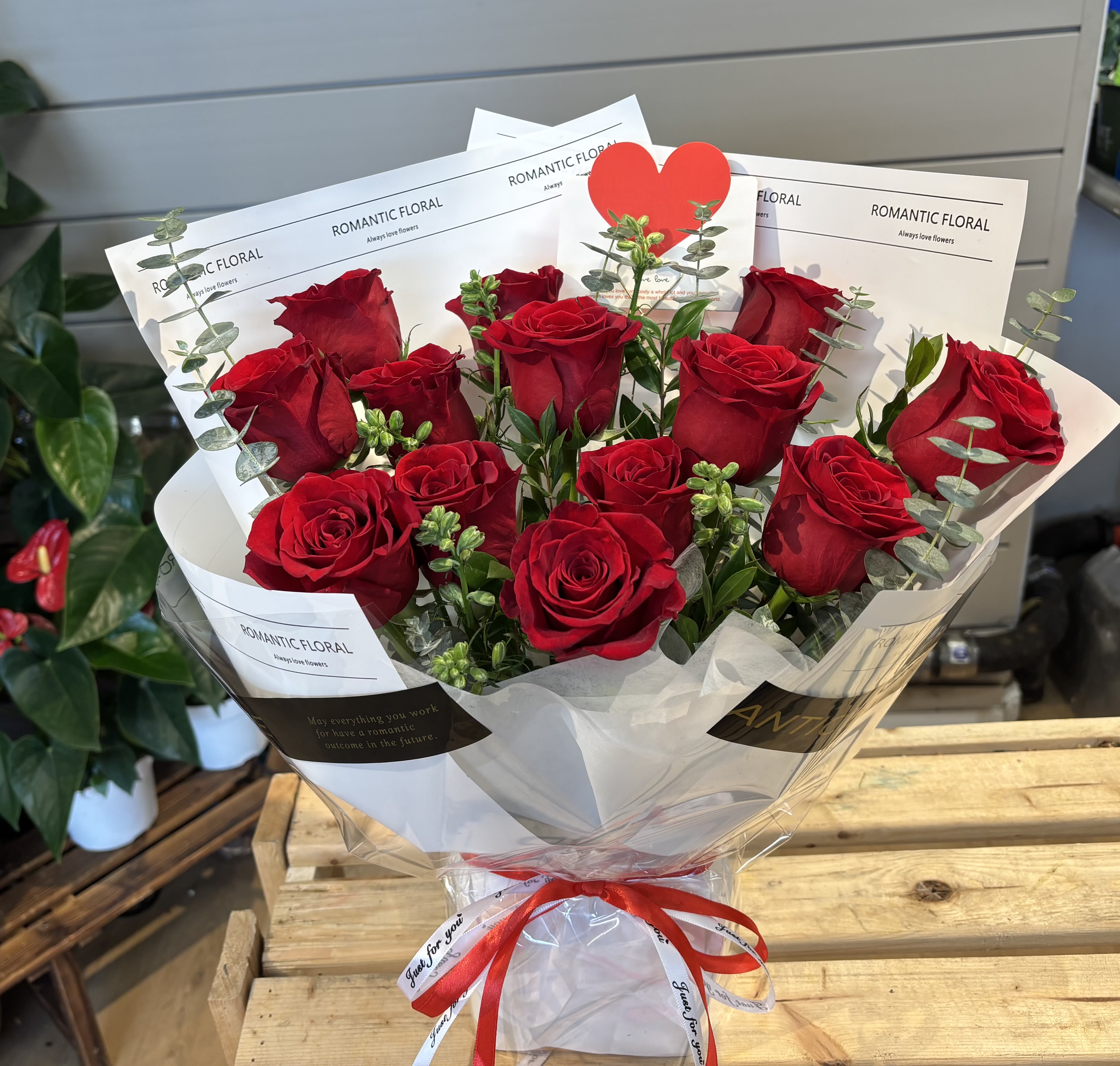 Bouquet of red roses wrapped in white paper with a red ribbon