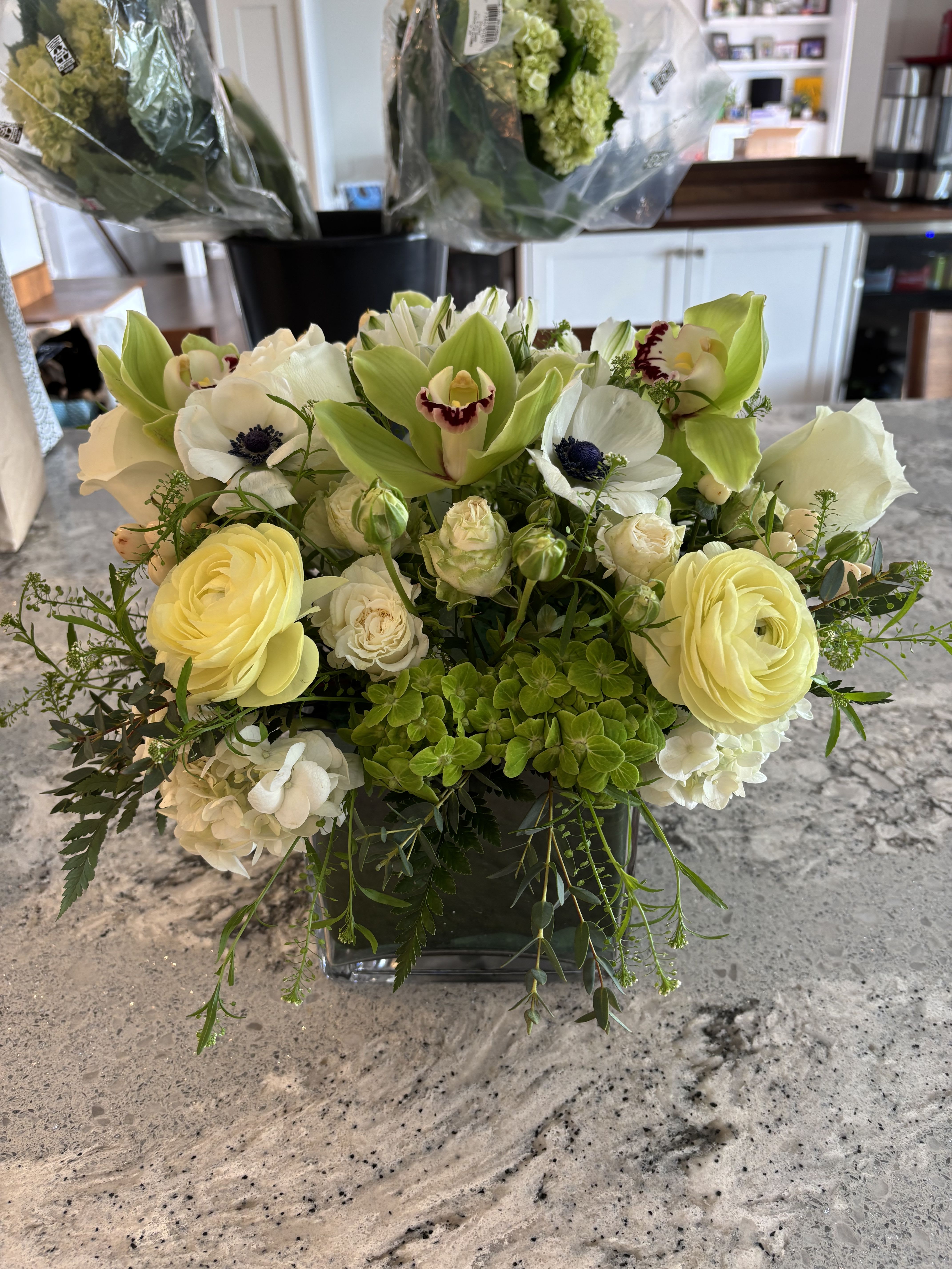 Cream and green floral arrangement in a square glass vase