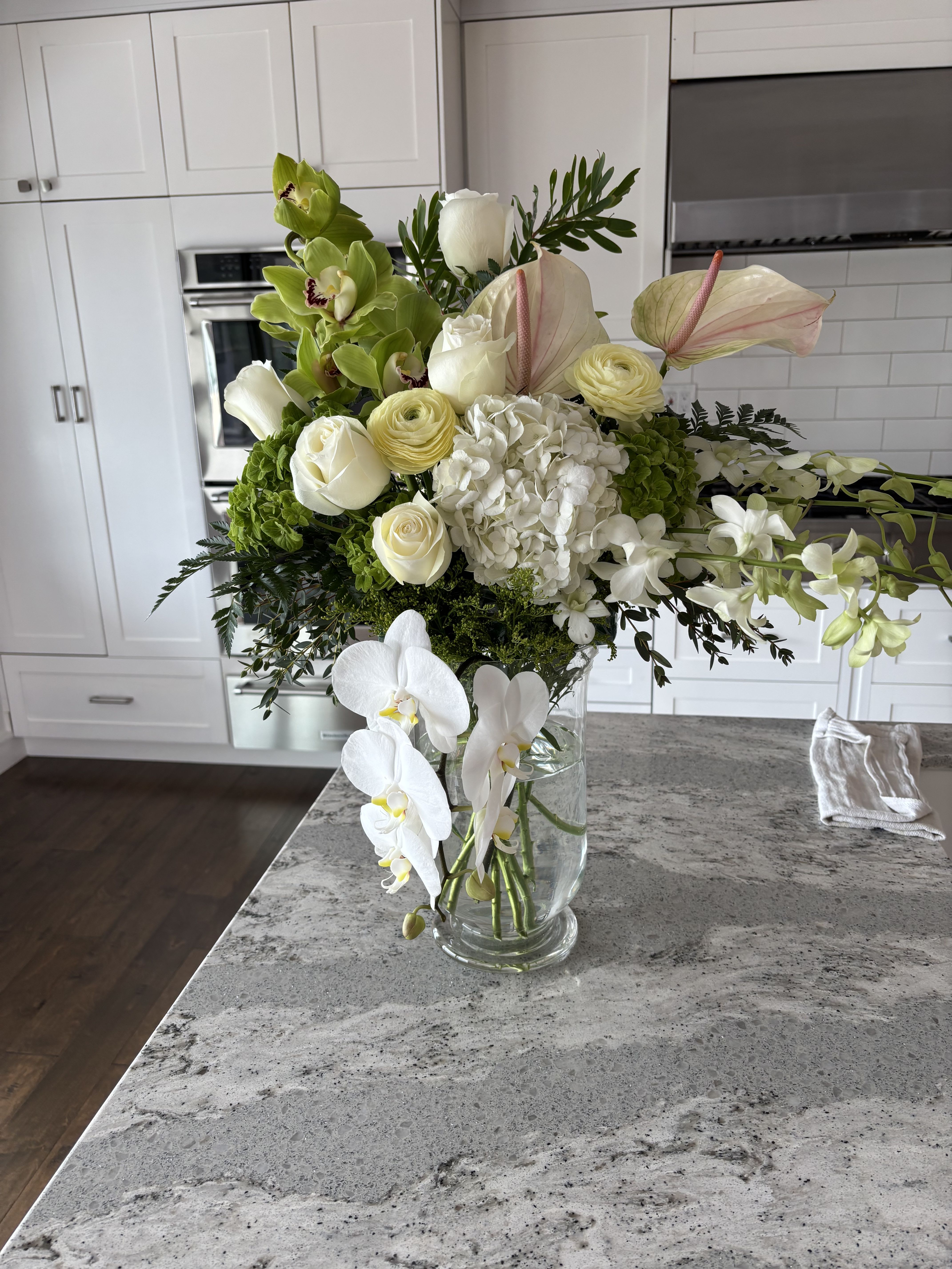 White and green floral arrangement in a clear glass vase